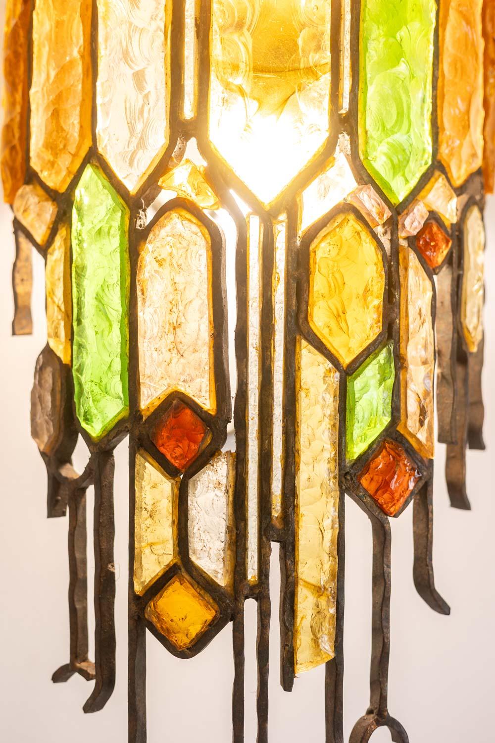 Wandleuchte aus Schmiedeeisen und farbigem Glas.

Italienisches Werk aus den 1960er Jahren.

Abmessungen: H 113 x B 32  x T 25 cm

Aktenzeichen: LS6480709M