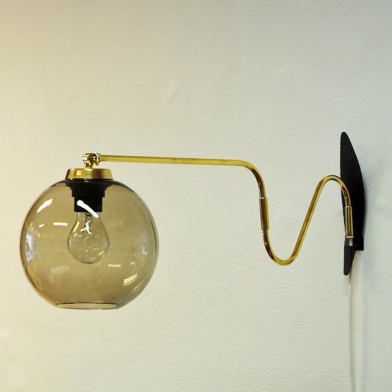 Midcentury wall lamp on an adjustable brass arm with a smoked glassdome by Høvik Verk, Norway, 1950s. The lamp can be adjusted to the left, right and straight ahead. Mounted on a black metal grid for wall fixing. A great lamp for all rooms! Good