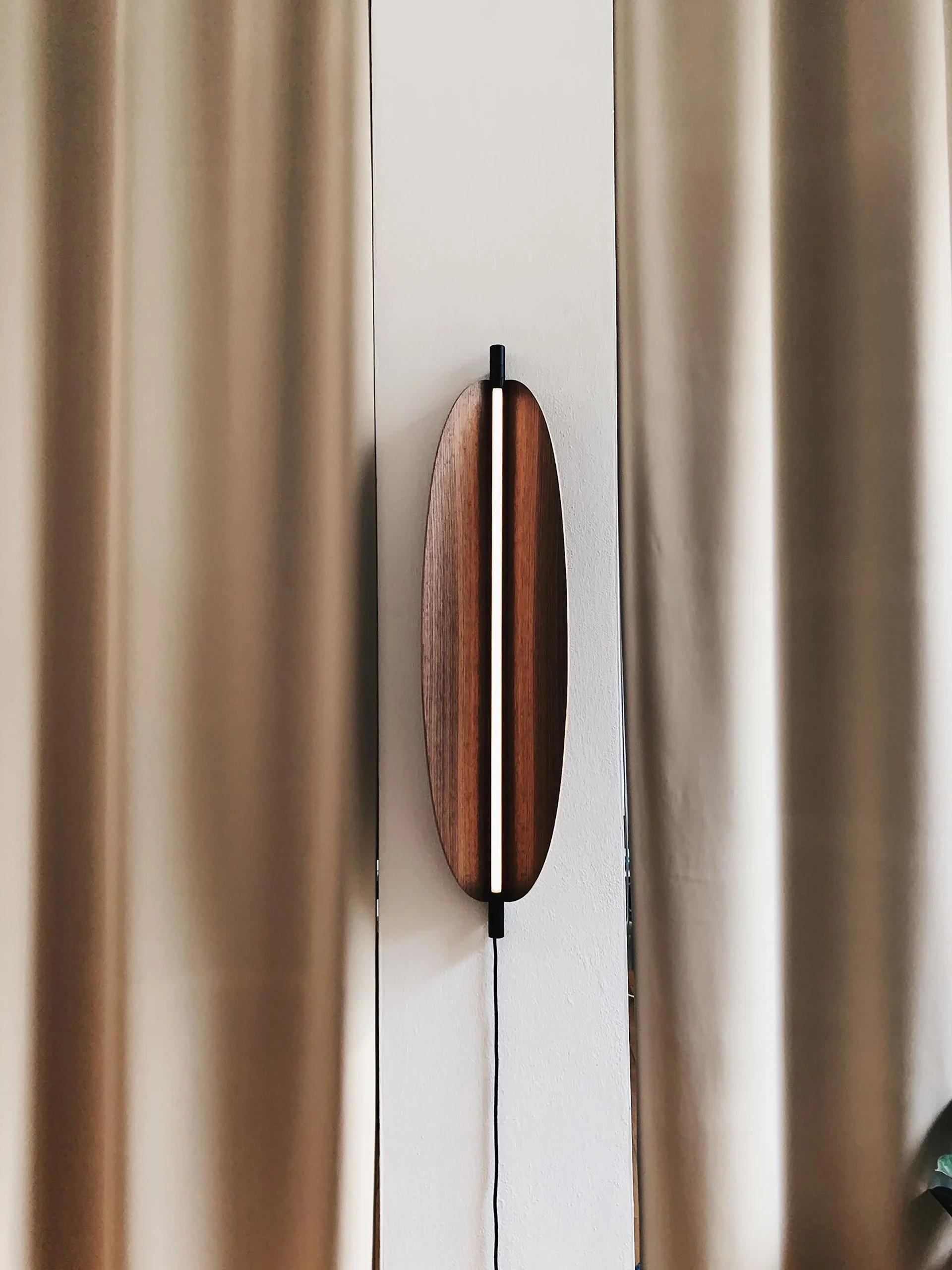 Thula 562.42 by Frederica Biasi x Tooy
Wall lamp
Compliant with USA electric system

Model shown: 
- hardware Sand black 
- details Satin nickel
- shade Canaletto walnut

Materials: aluminum, metal, leather, wood

The Thula wall lamps are based on a