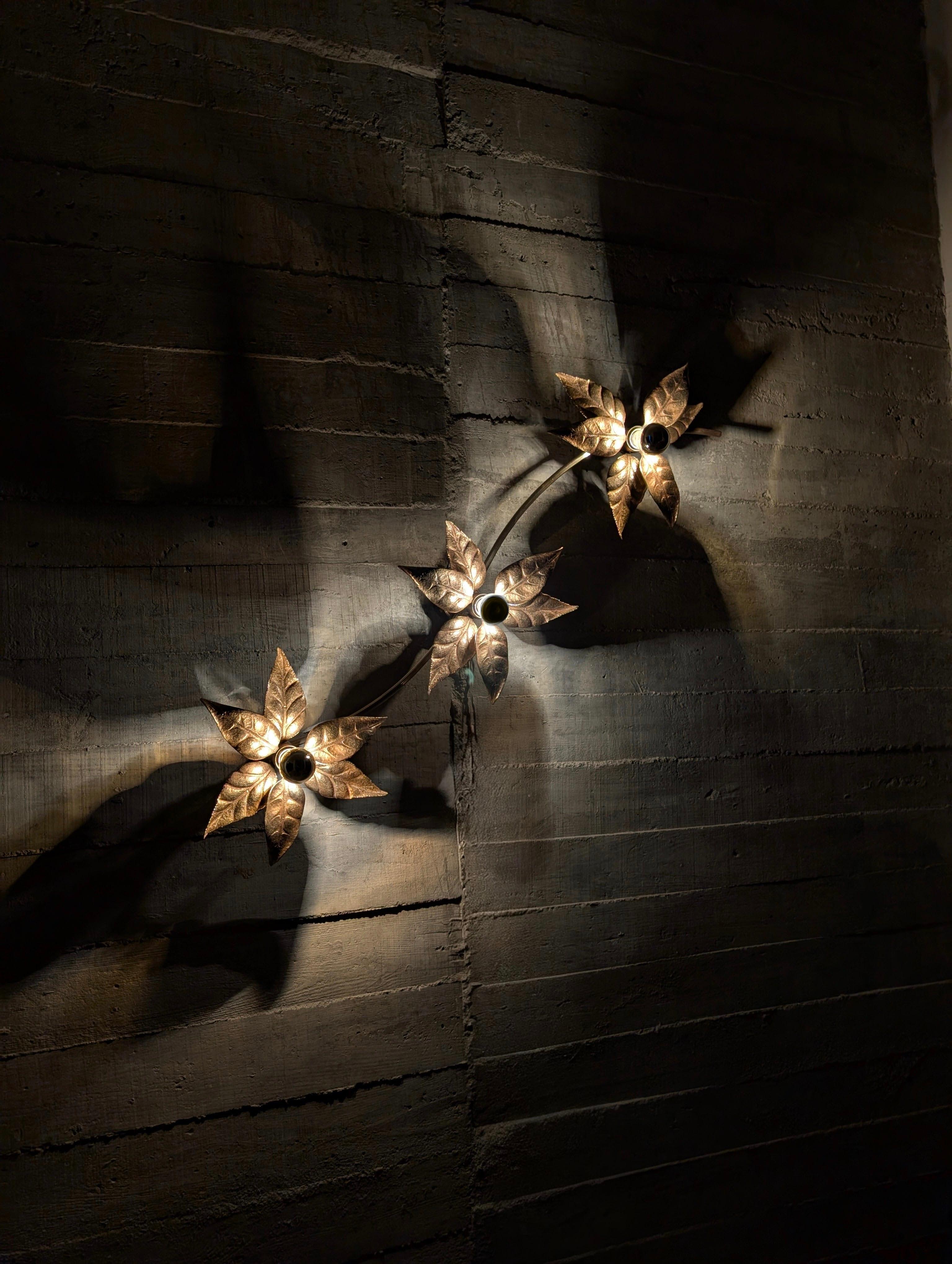 Floral wall lamp designed by Willy Daro made of gold metal and brass in the 1970s. Each point of light has beautiful golden leaves around it creating a beautiful decoration and ambient light.