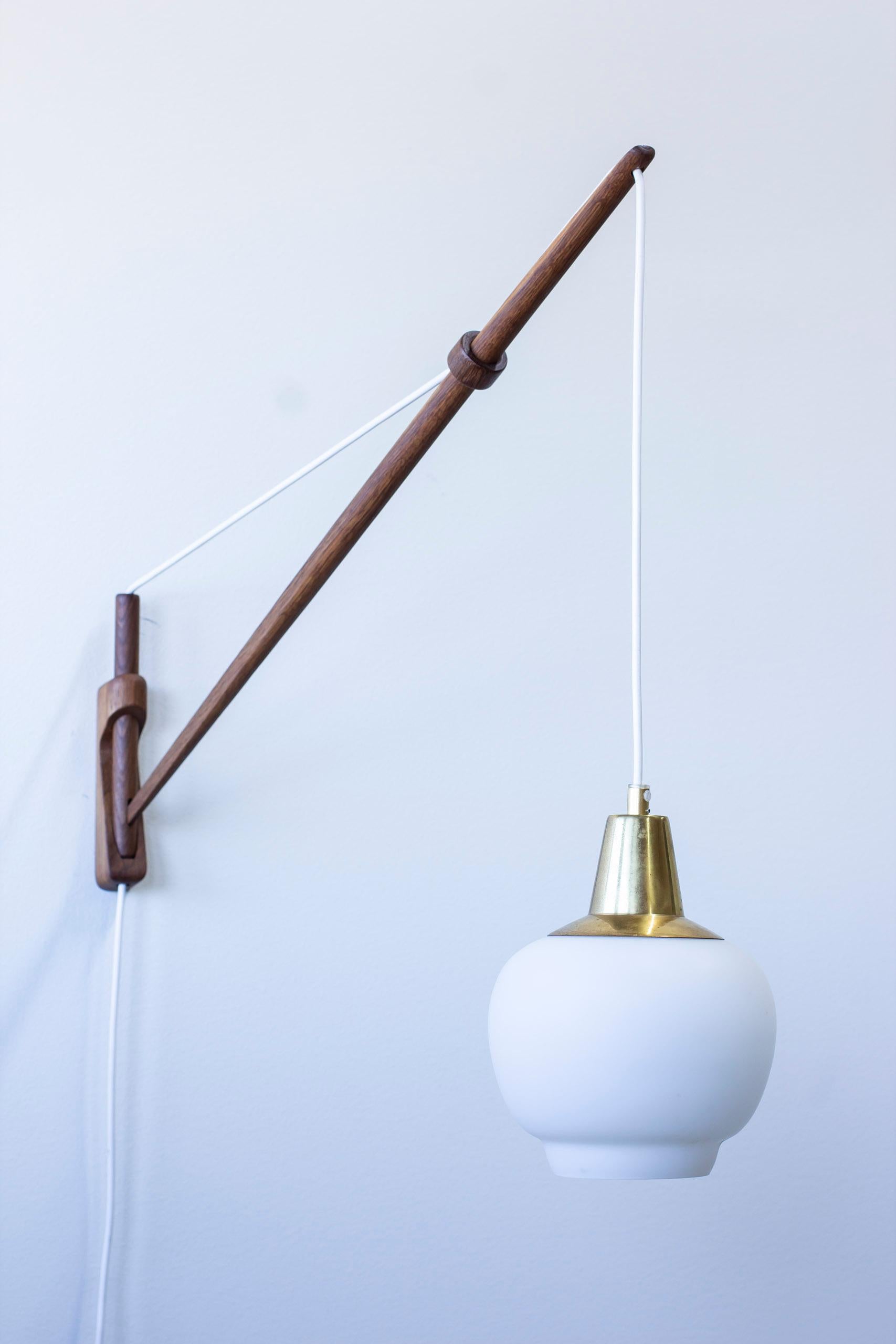 Wall lamps designed by O. Bank Larsen and Kjeld Iversen. Produced in Denmark by Louis Poulsen during the 1950s. Made from solid oak with opal glass shades with brass top. The chord of the lamps can easily be extended with the smart solution of the
