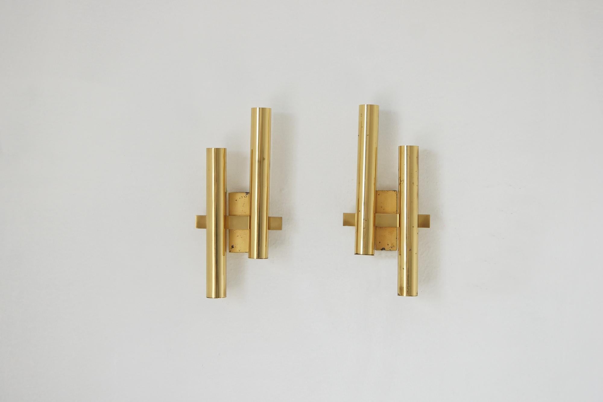 Un conjunto de apliques minimalistas del renombrado diseñador italiano Gaetano Sciolari es un sofisticado ejemplo de enfoque modernista de la forma, la luz y la geometría.

La estética característica de Sciolari combina la sencillez de líneas con la