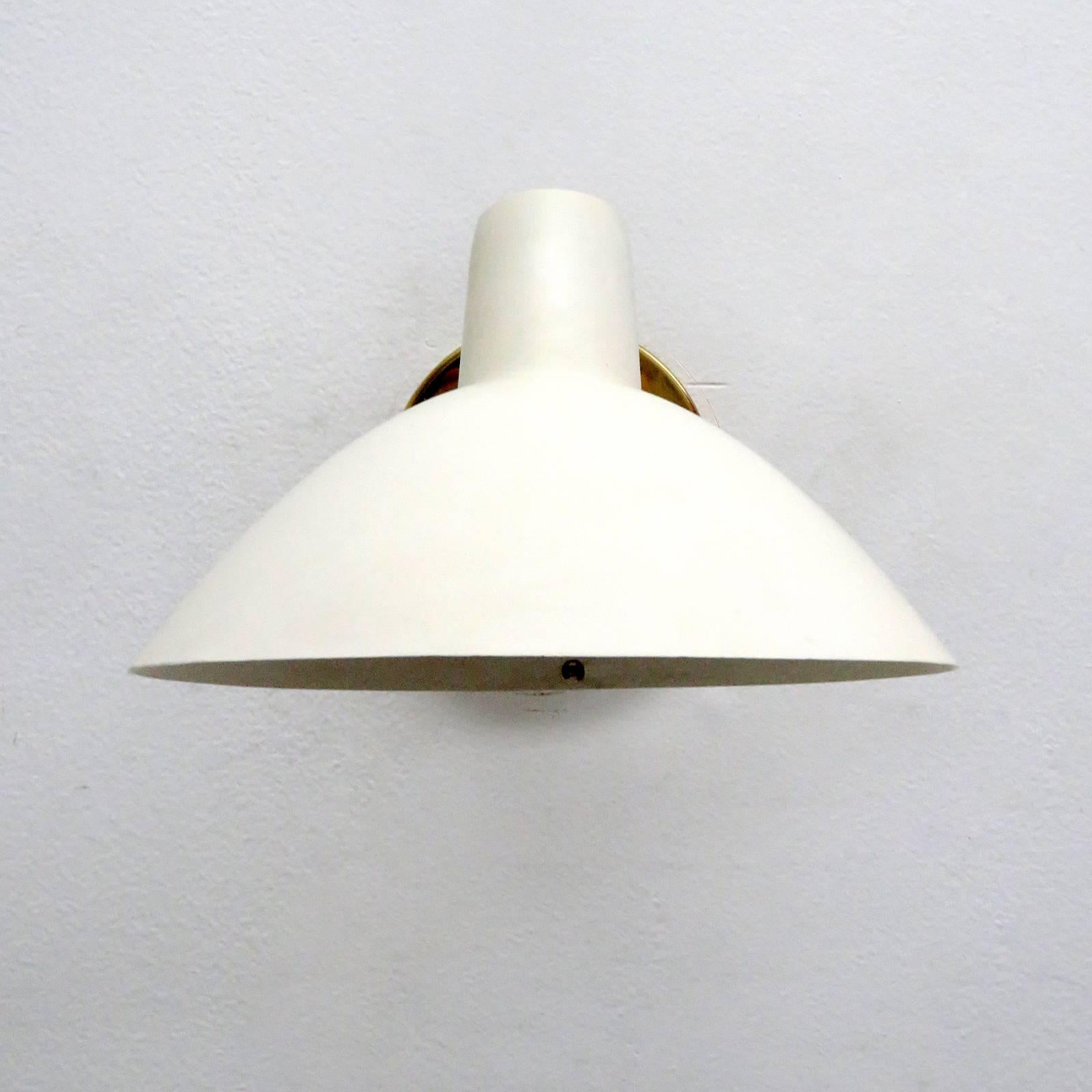 Wonderful 'Visor' wall light by Vittoriano Vigano for Arteluce designed in Italy, 1950s, egg shell colored enameled aluminium, brass, can be mounted in an upward or downward position, shade articulate left/right, on/off switch on the brass back