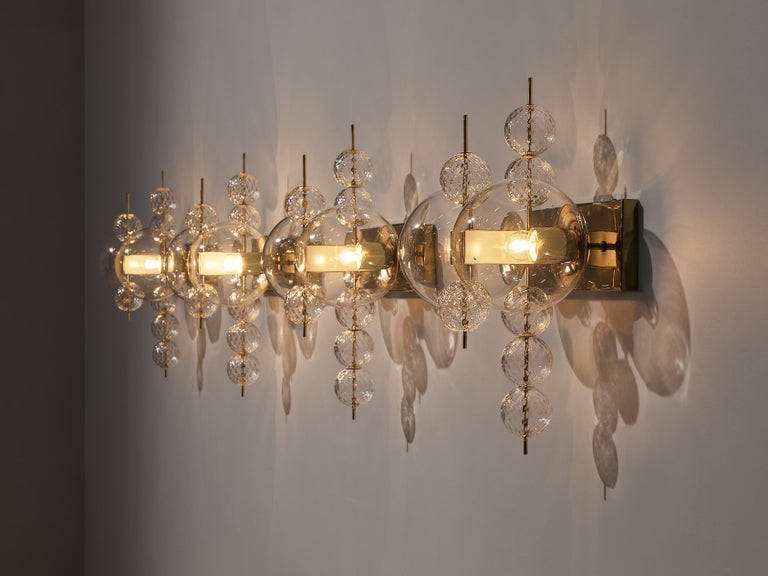 Chandelier in glass and brass, Europe, 1970s.

Ornate brass and glass wall light with two-light points and small decorative structured glass globes. The chandelier is beautifully decorated thanks to the structured glass. The clear glass shades