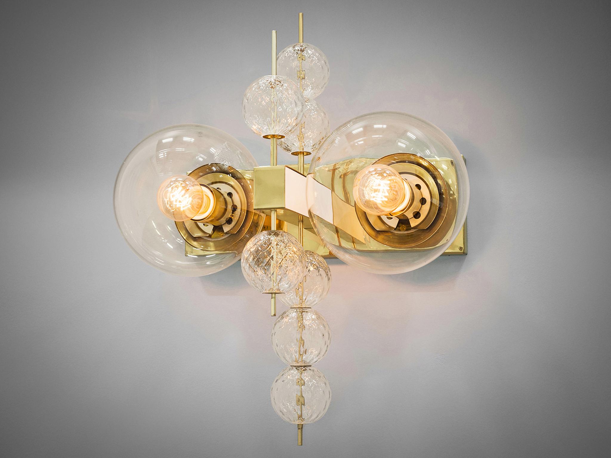 Wall light, glass and brass, Europe, 1970s.

Ornate brass and glass wall light with two-light points and small decorative structured glass globes. The chandelier is beautifully decorated thanks to the structured glass. The clear glass shades bring a