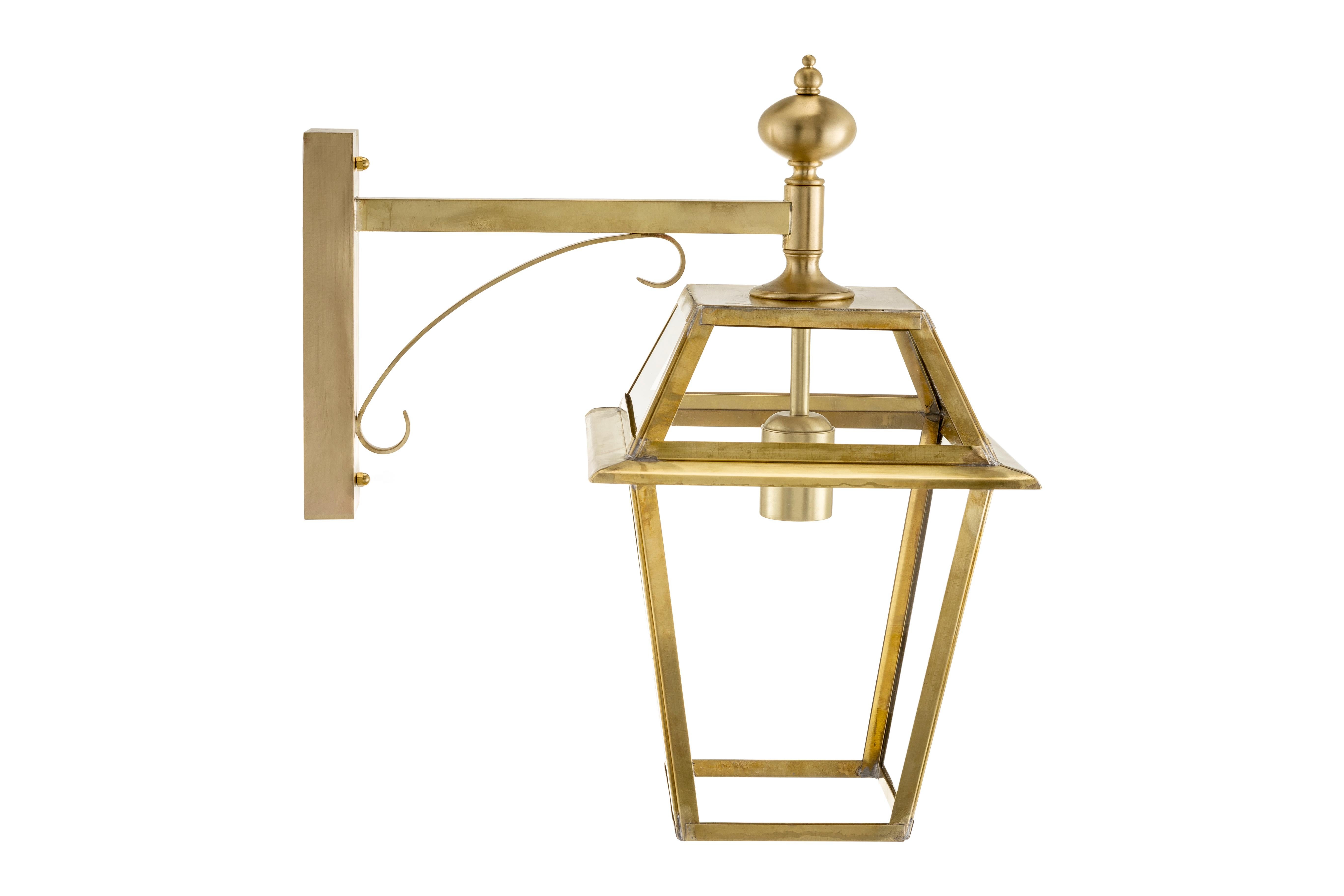 Novecento 333 natural brass applique with transparent glasses. It pertains to the Timeless collection in which classical objects, lamps and furniture coexist together with pieces reinterpreted in more contemporary shape. This lantern model is called