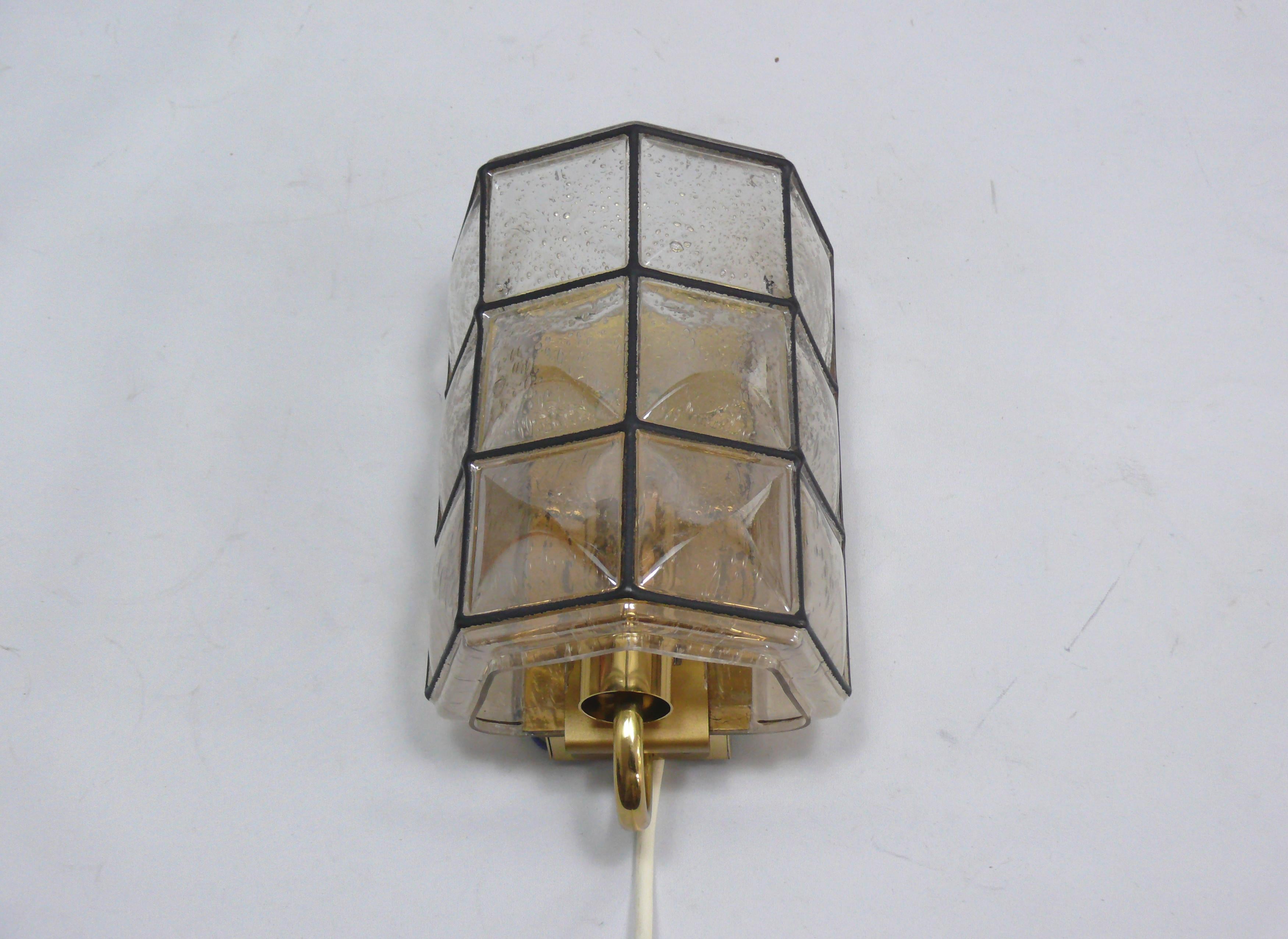 Applique murale de Glashütte Limburg de la période 1970-1979, modèle A 495. Le luminaire se caractérise par une fabrication de haute qualité et un design minimaliste. L'abat-jour en verre légèrement incurvé est visuellement divisé en plusieurs