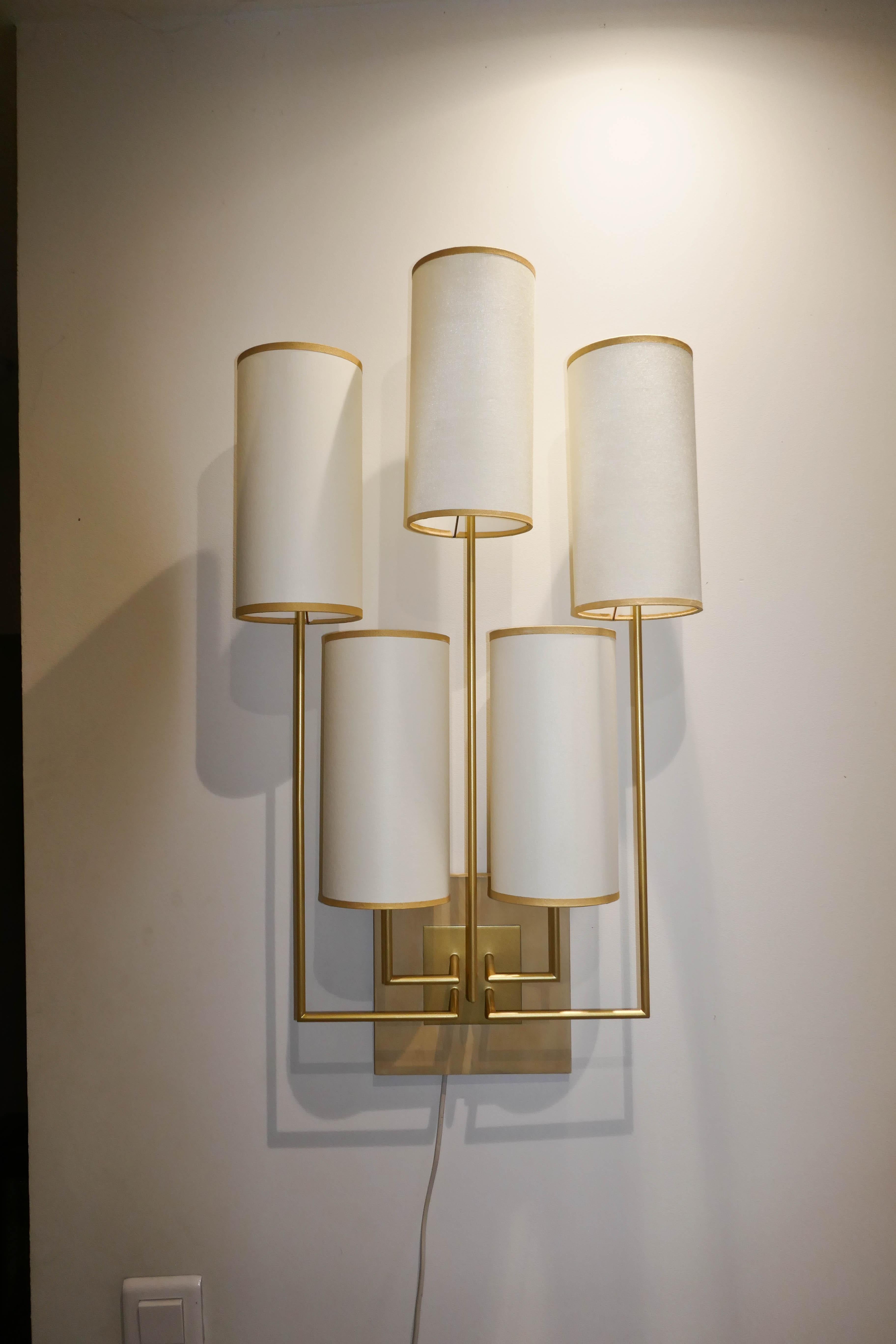 Wall light, sconce in gold patina metal, the base is in chestnut wood. There are five lampshades in white fabric.
This wall lamp is new but has been used for an exhibition.
This is for one item but can be sold as a pair.
Information about the covid