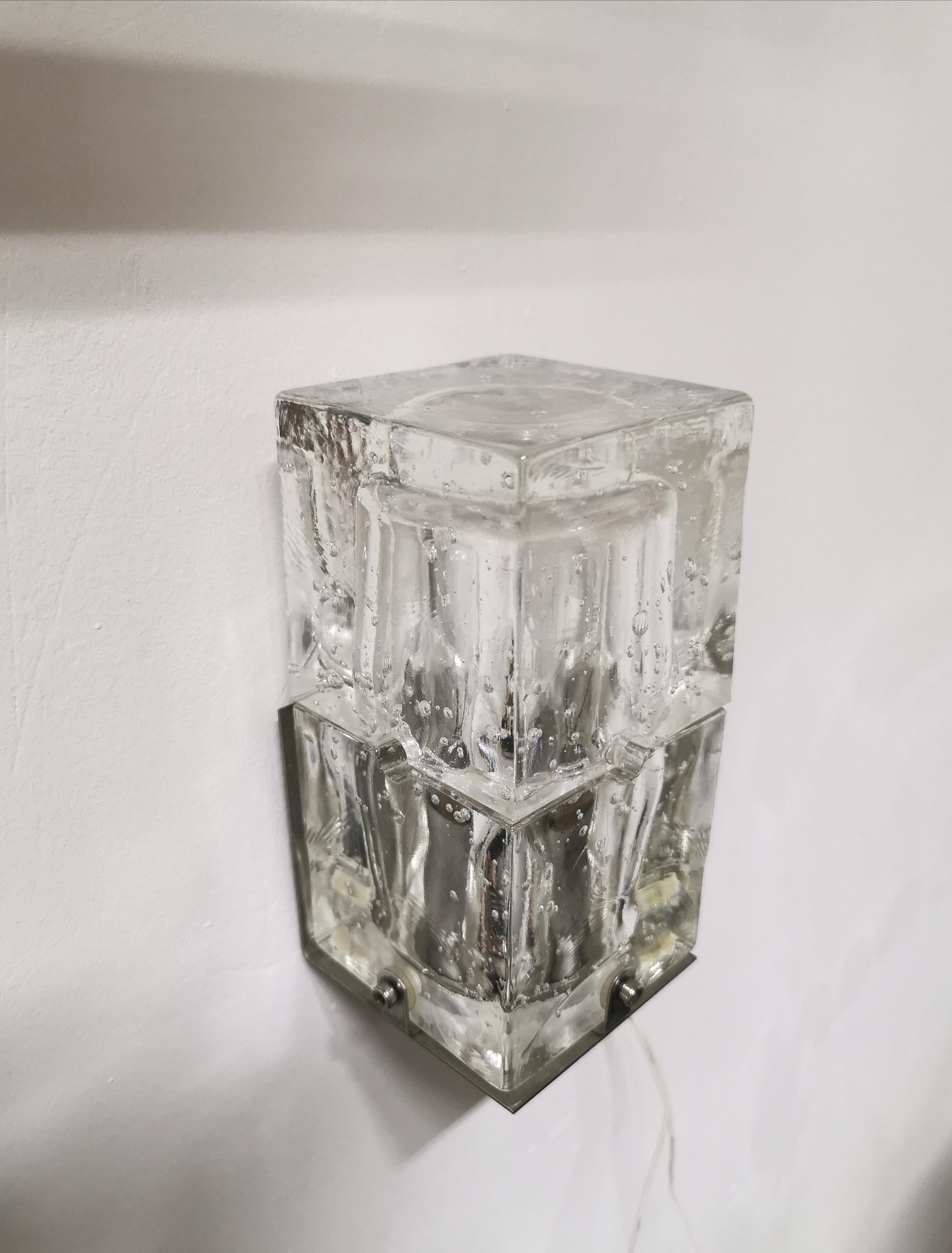 Small wall lamp by an unknown designer produced in Italy in the 70s. The lamp has an aluminum structure which, by means of screws, supports a cubic bubble-shaped Murano glass.