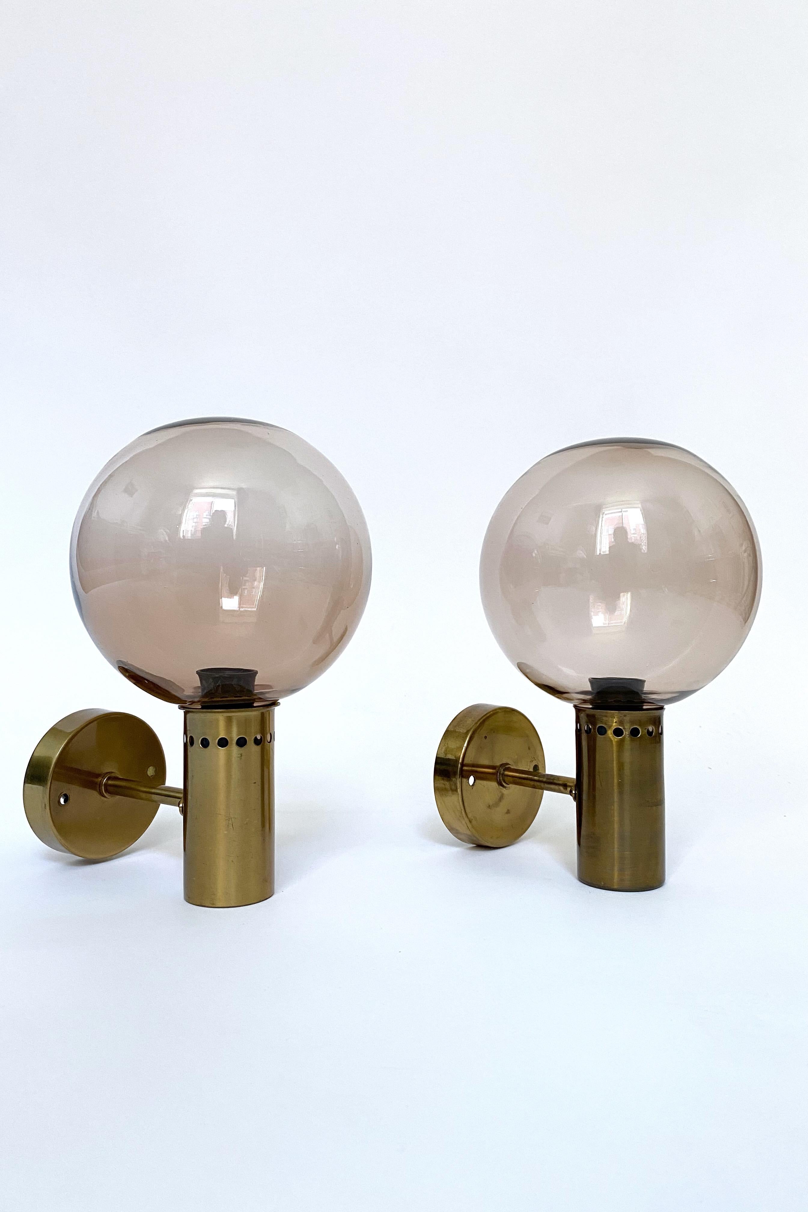 Wall lights in model S-1987 by the iconic Swedish lamp designer Hans Agne Jakobsson for his eponymous company in Markaryd, Sweden.

Made in the 1950's this is the model S-1987 with brass holder and smokey pink glass globes. Age appropriate wear to