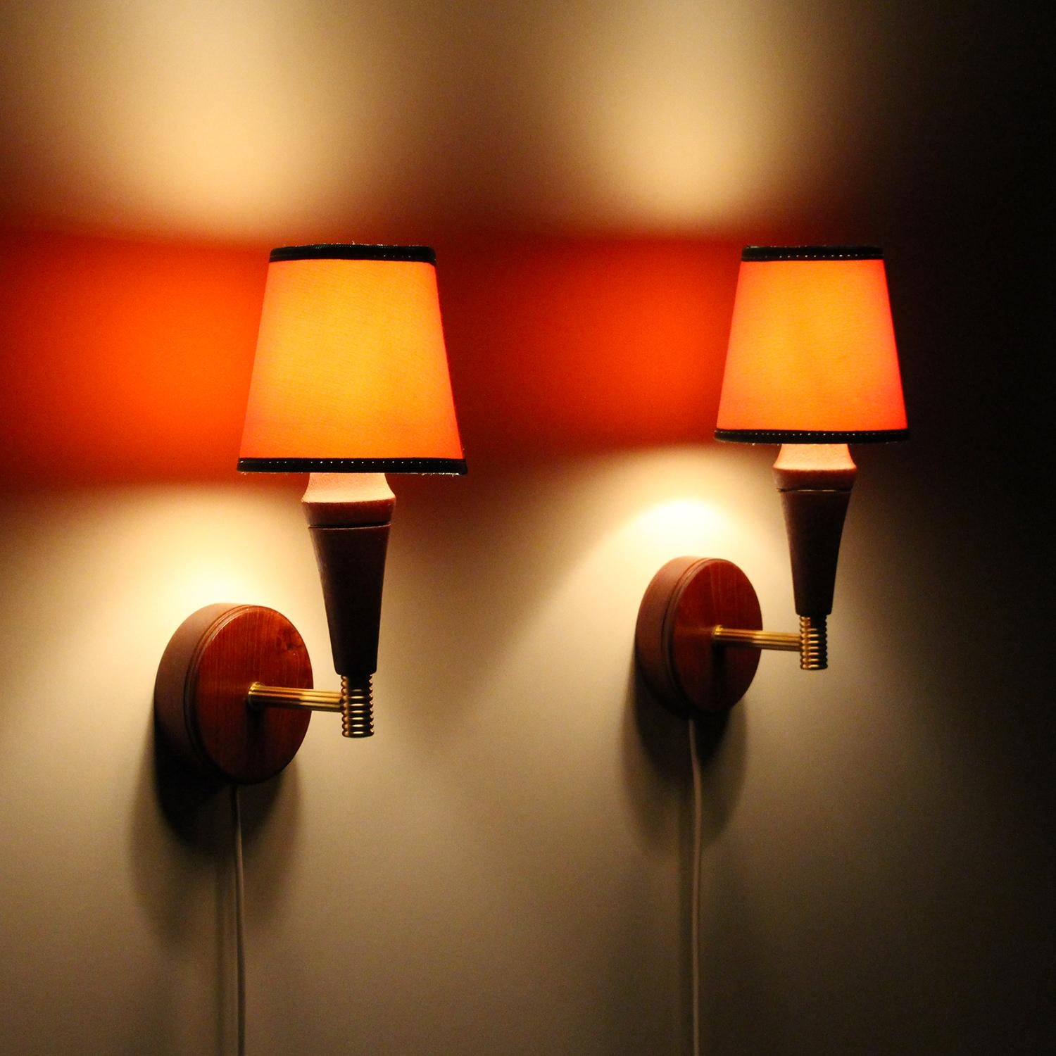 Wall Lights - pair of 1950s Danish midcentury wall lamps with vintage orange textile shades, all in very good vintage condition.

A charming pair of midcentury sconces, each comprised of a round wooden base, a straight polished brass arm holding a