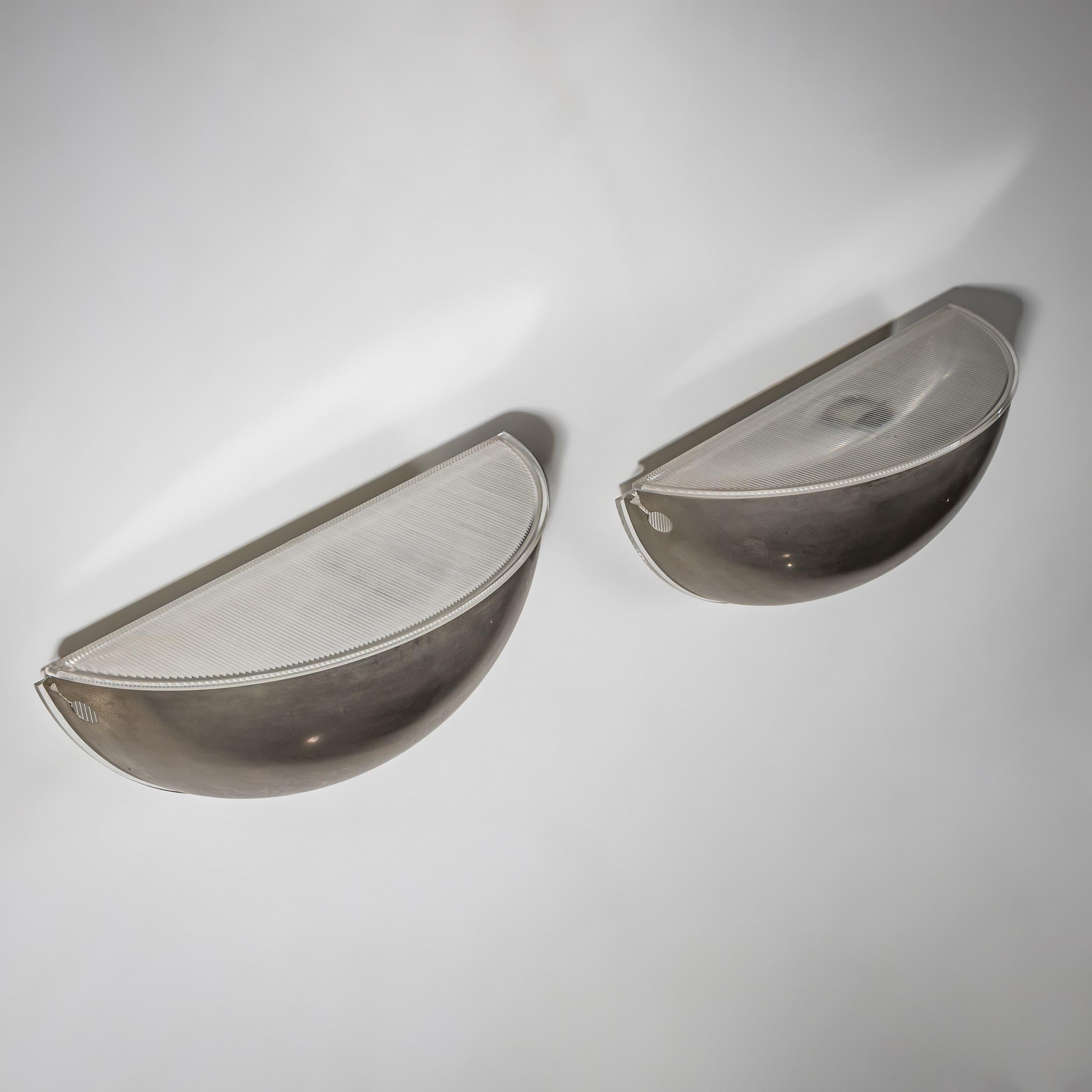 Este par de apliques en forma de cuarto de esfera fue diseñado por Tobia Scarpa para FLOS. Son de aluminio y cristal estriado. Cada uno lleva un sello en el reverso.