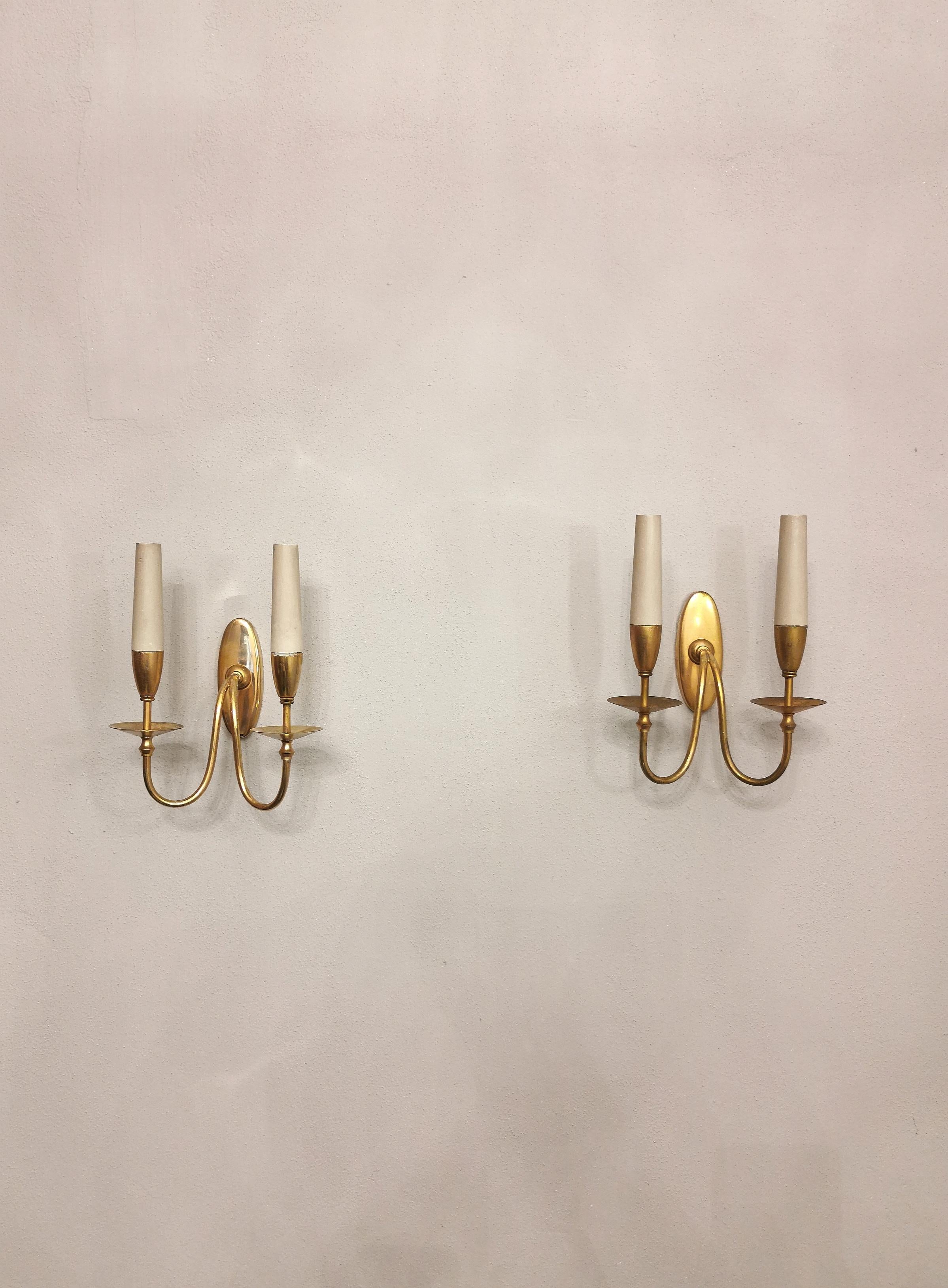 Elegant set of 3 wall lamps from the 1940s designed by the renowned Italian designer Gio Ponti. Each single lamp has an oval-shaped wall housing with a stamp behind it and two curved brass arms that support two 1-light E14 lamp holders in enamelled