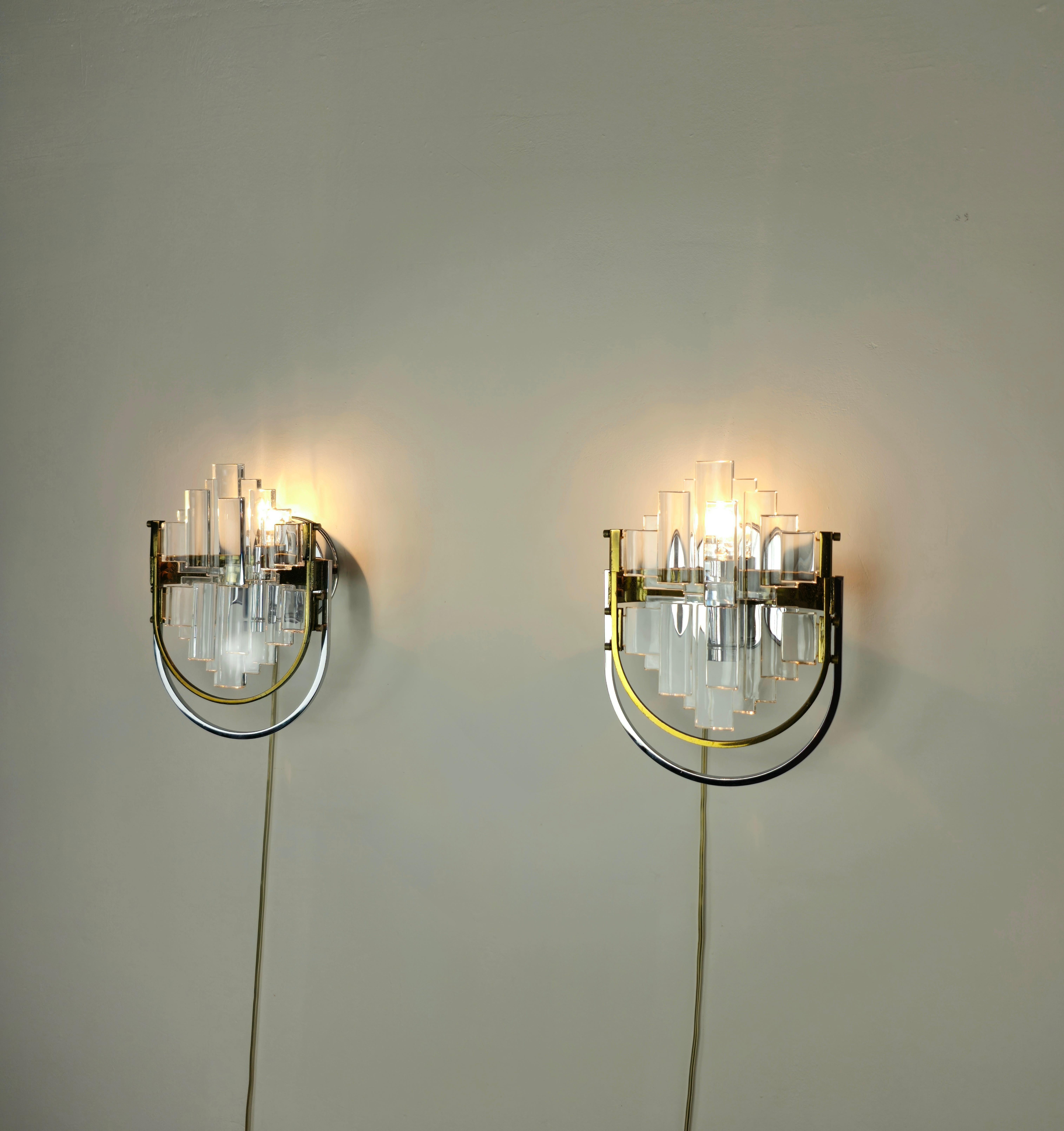 Set of 2 wall lamps produced in Italy in the 70s by Gaetano Sciolari for Stilkronen.
Each individual wall lamp has a chromed and gilded metal structure which supports two transparent glasses of a particular shape.



Note: We try to offer our