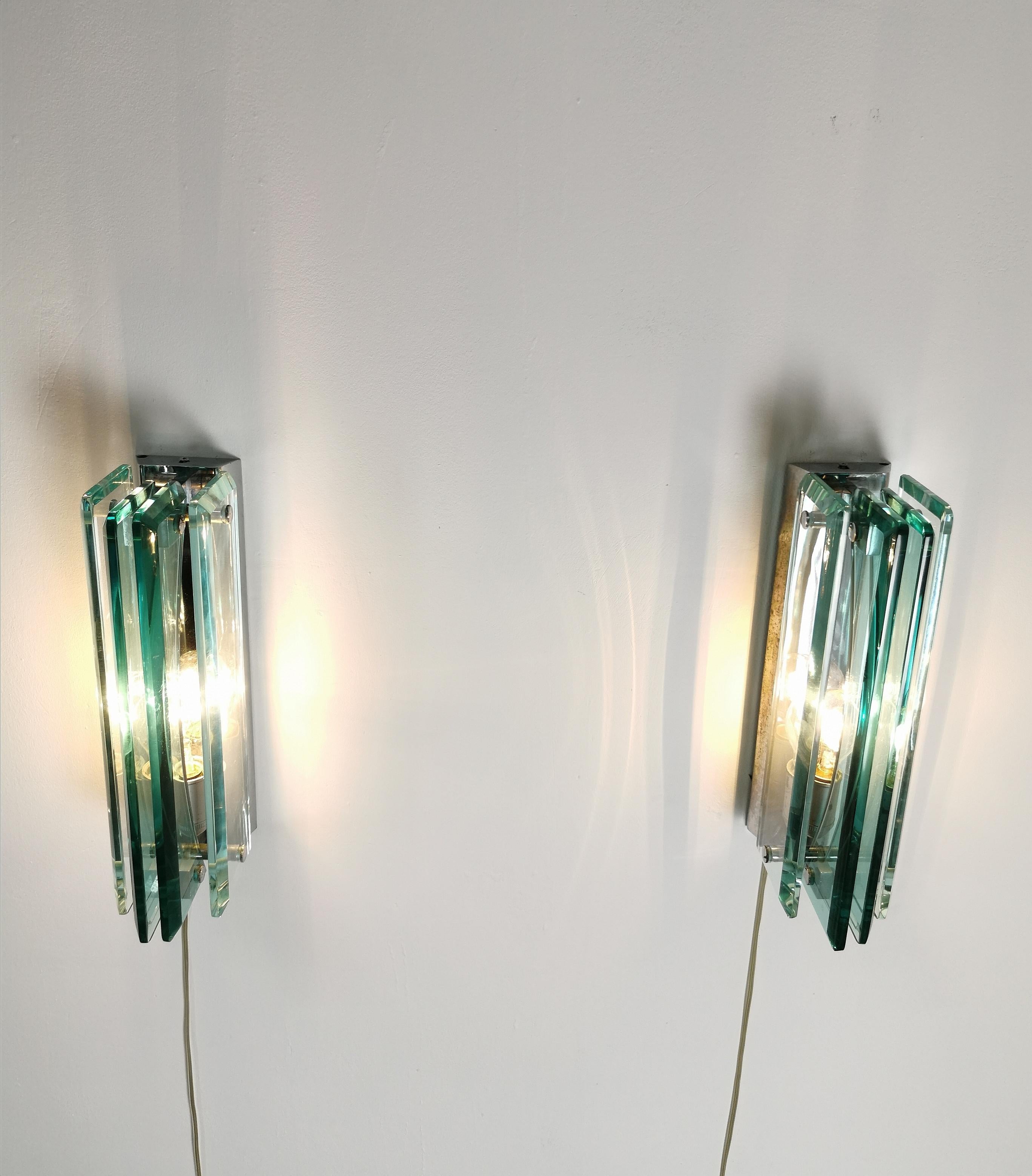 Elegant pair of wall lamps produced in the 70s and attributed to the famous Italian company Cristal Art. Each individual wall lamp was made with a metal and chromed brass structure which supports 2 rectangular Murano glass plates on the outside