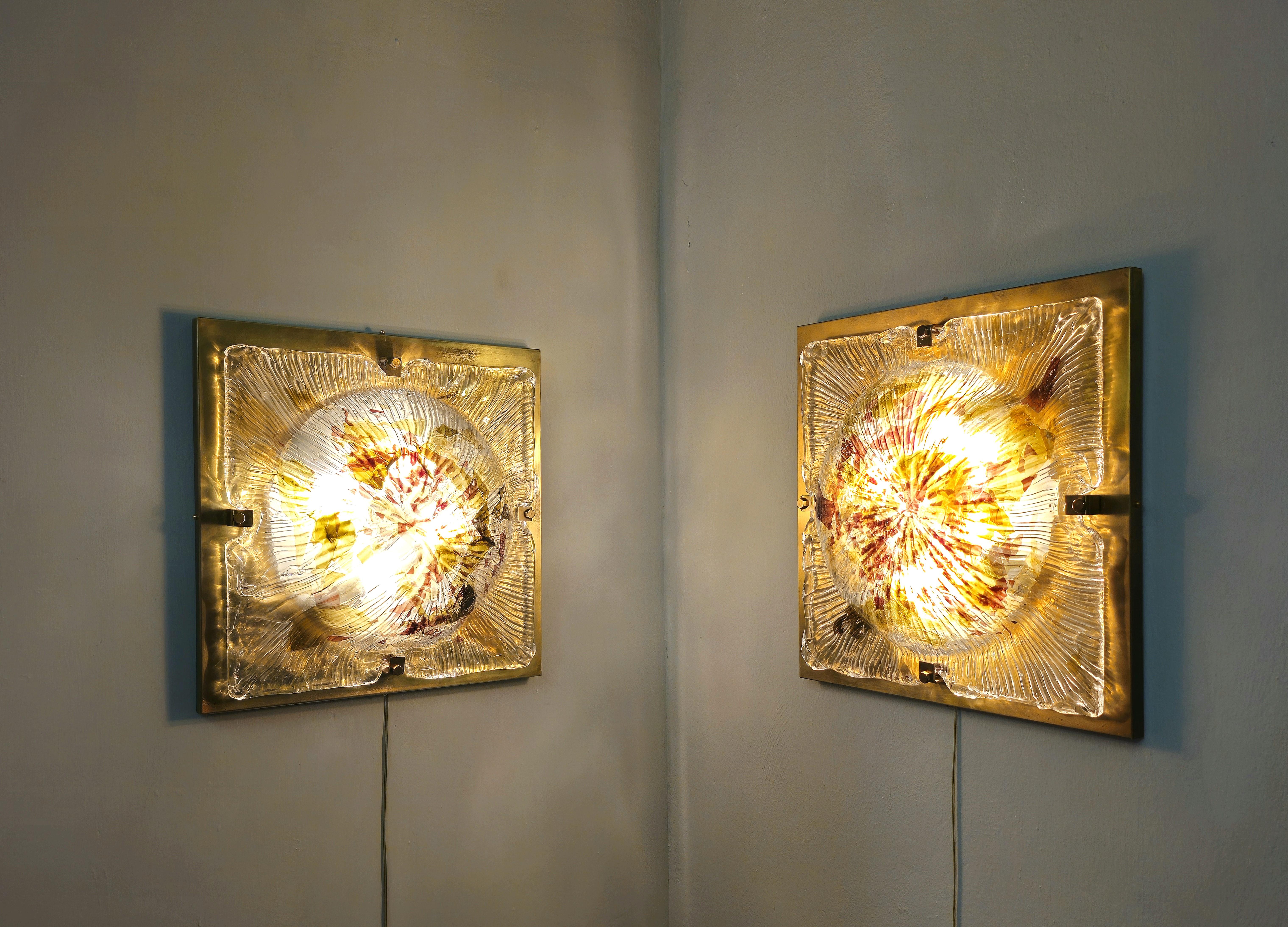 Large set of 2 wall lamps by Italian designer and produced in the 1970s. Each single lamp was made with a 4-light structure in white enamelled metal, superimposed on a sheet of brass and solid multicolored Murano glass. They can also work as ceiling