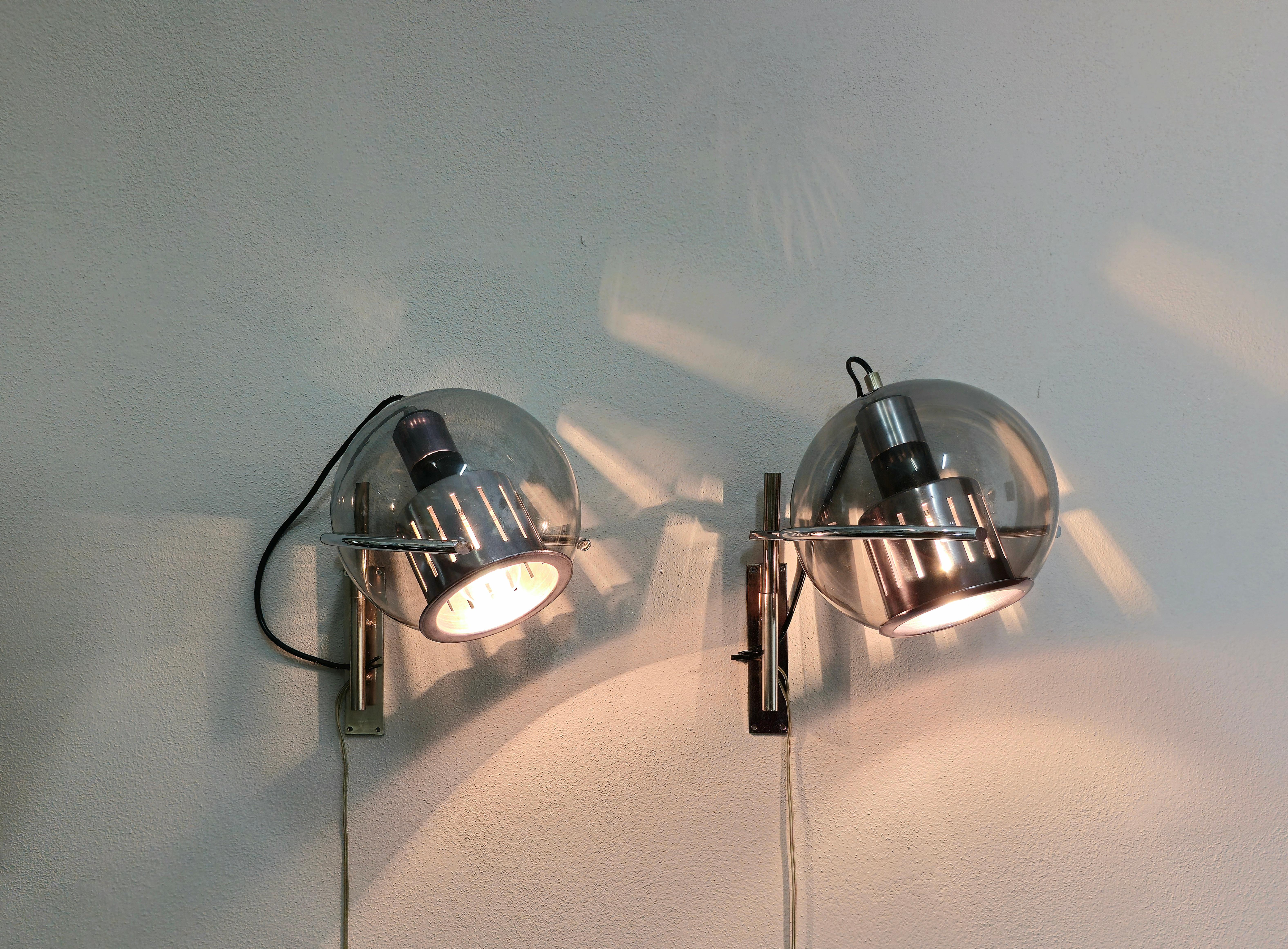Set of 2 wall lamps made in Italy in the 1960s and designed in the style of Luigi Caccia Dominioni.
Each single multifunctional wall lamp was made with a brass and chromed metal structure and a spherical smoked glass diffuser.


Note: We try to