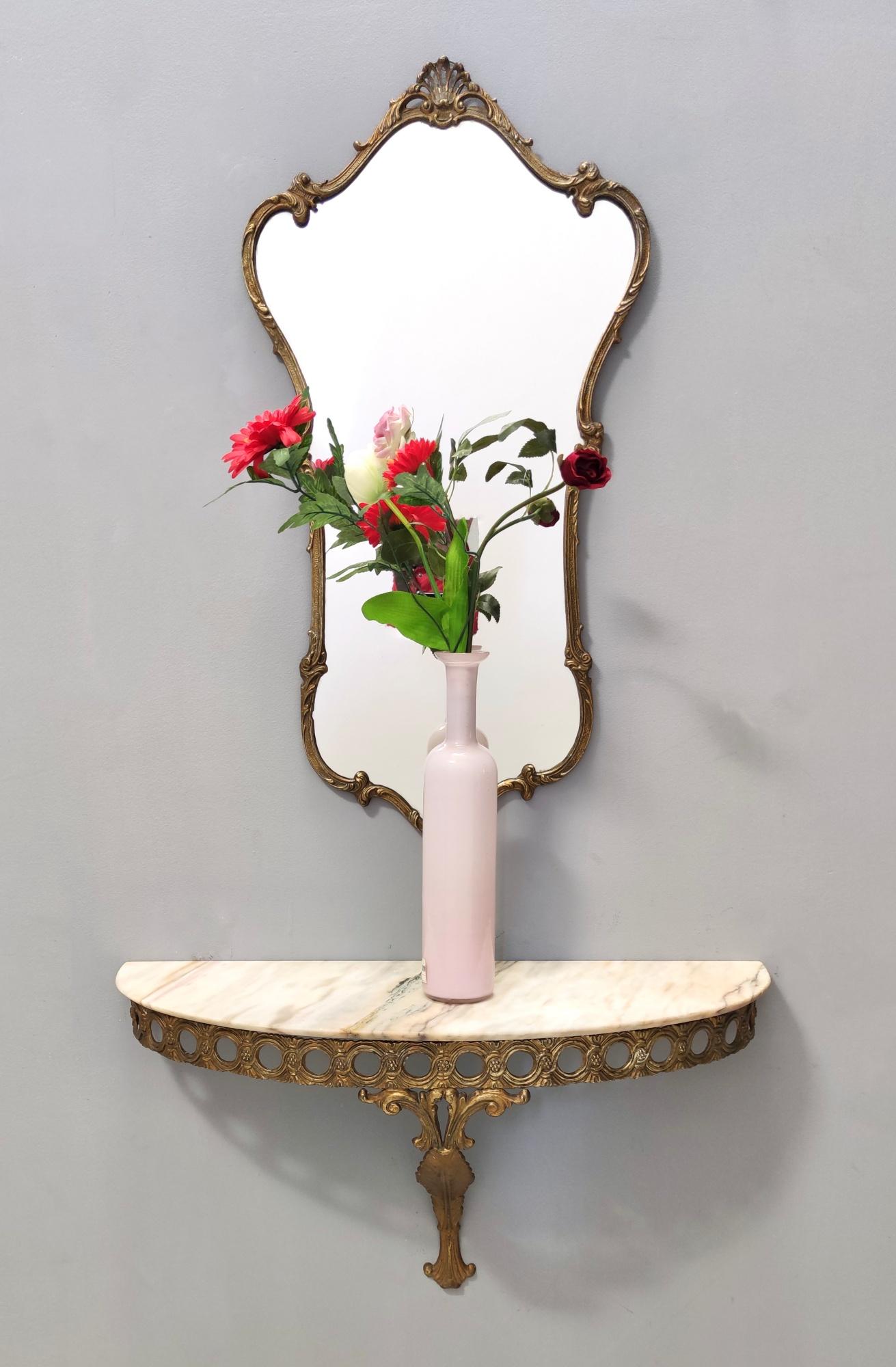 Italy, 1950s.
The wall-mounted console table features a demilune Portuguese pink marble top and both the mirror and the console have a varnished brass and metal frame.
They might show slight traces of use since they are vintage, but they can be