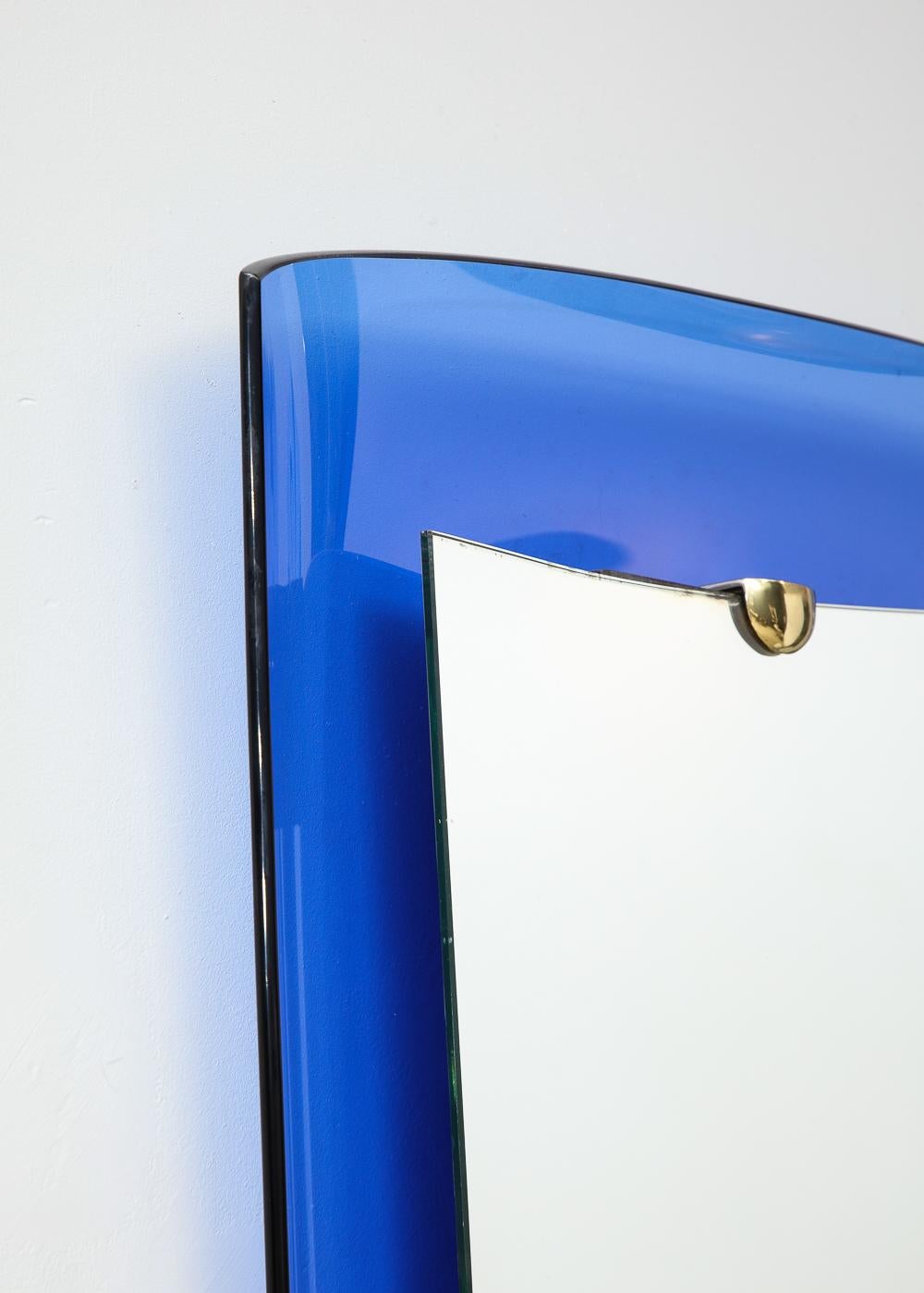 Verre, miroir, laiton. Le modèle #2712 de Cristal Art présente un cadre concave en verre bleu avec un centre en miroir surélevé maintenu par des ferrures en laiton.