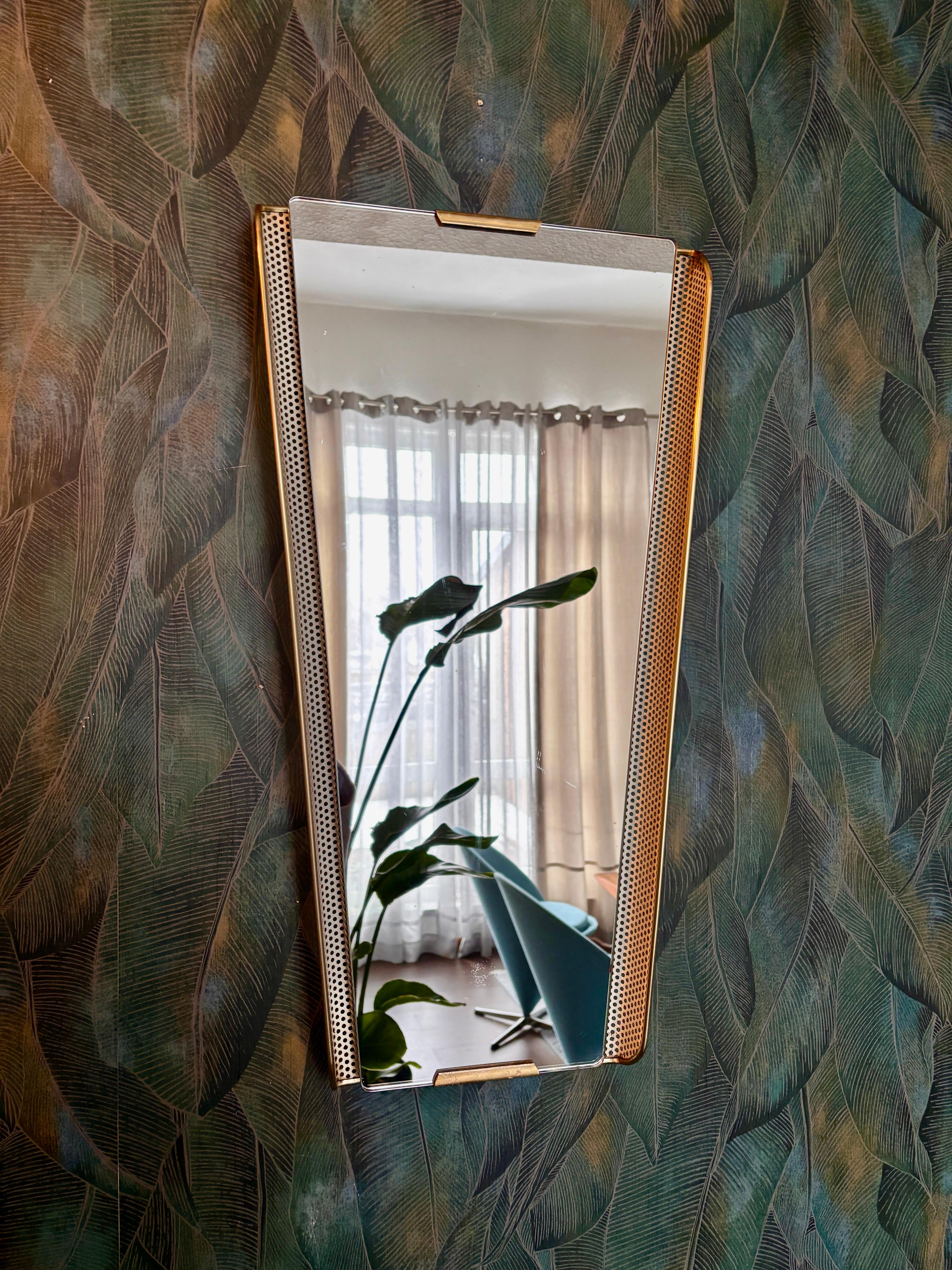 Uno specchio delicato, molto bello e raro, realizzato in Germania negli anni '50.
Lamiera forata verniciata di bianco, racchiusa in una cornice di plastica in ottone.

Lo specchio è in discrete condizioni, usato e originale.
Presenta segni visibili