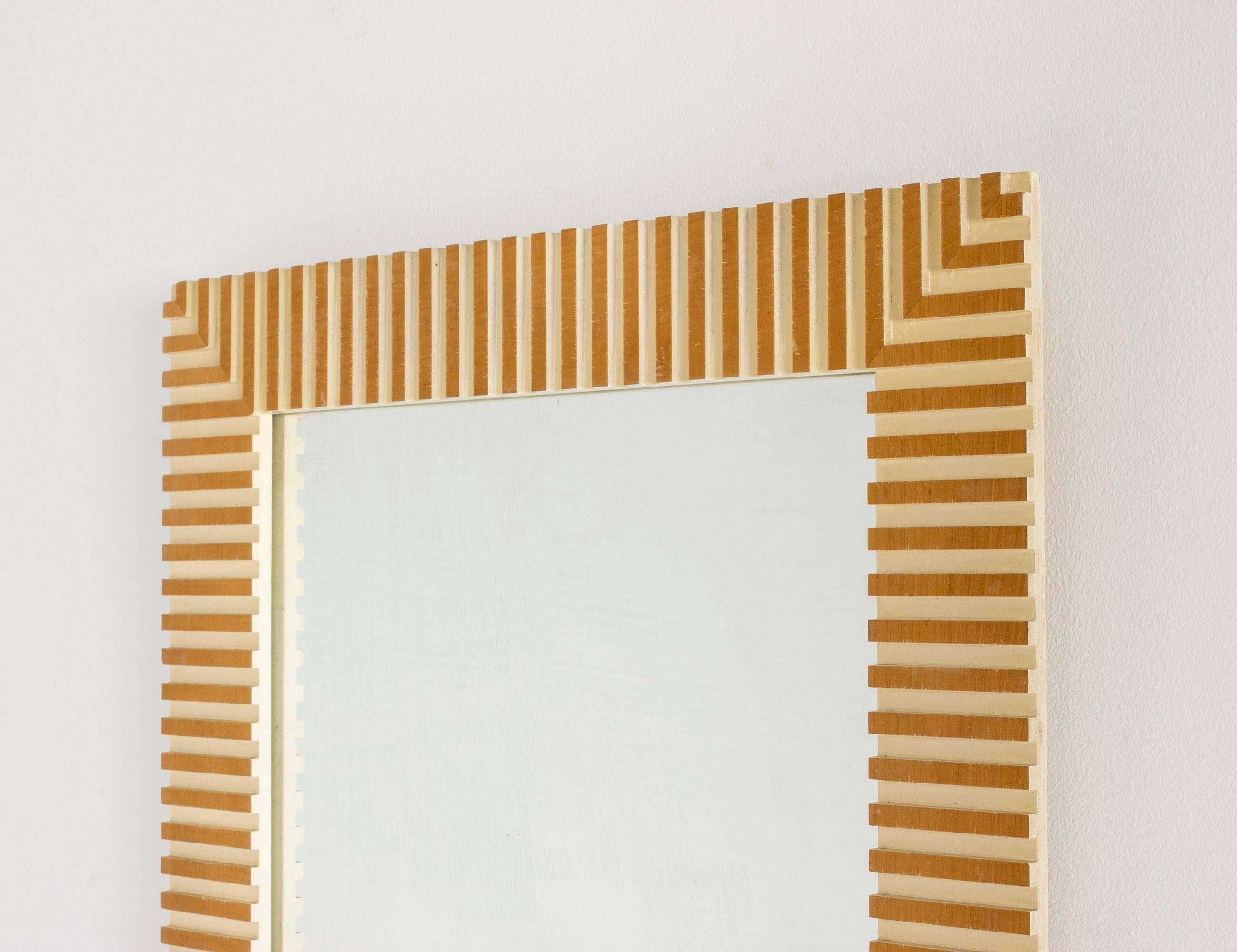 Striking, timeless wall mirror by Susanne Tucker and Maurice Holland, made from wood embossed in a geometrical fashion. Frame lacquered white inside the embossments, with wood exposed on the surface, giving an impression of it being gilded.