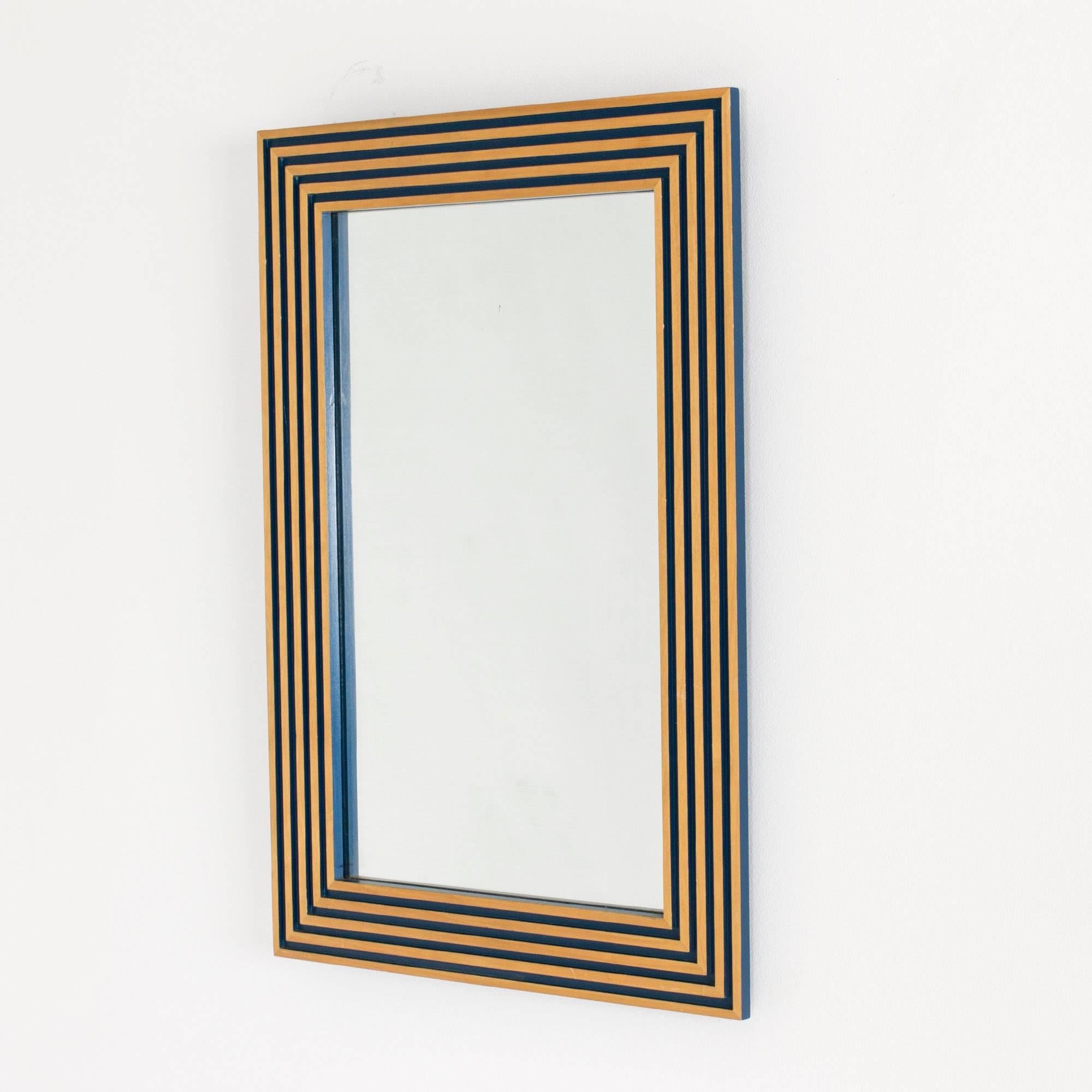 Miroir mural saisissant et intemporel de Susanne Tucker et Maurice Holland, fabriqué en bois embossé dans un motif géométrique. Cadre laqué bleu à l'intérieur des gaufrages, avec du bois apparent en surface, donnant une impression de dorure.