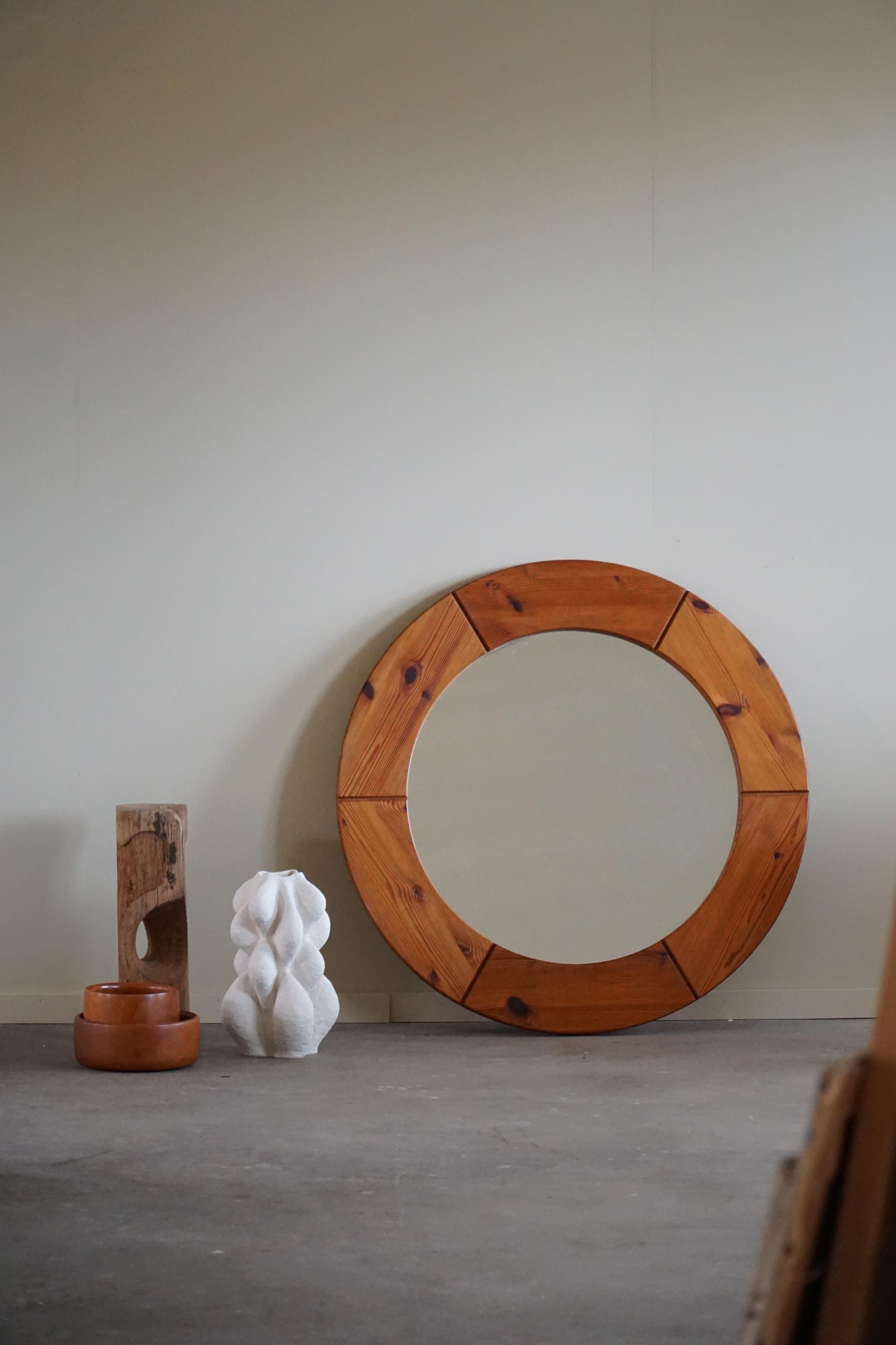 Large Round wall mirror in solid pine by Glasmäster Markaryd, Sweden, 1960. Labeled on the backside. The pine frame has a warm and natural finish, with the natural wood grain and knots adding a sense of depth and character to the piece. The frame is