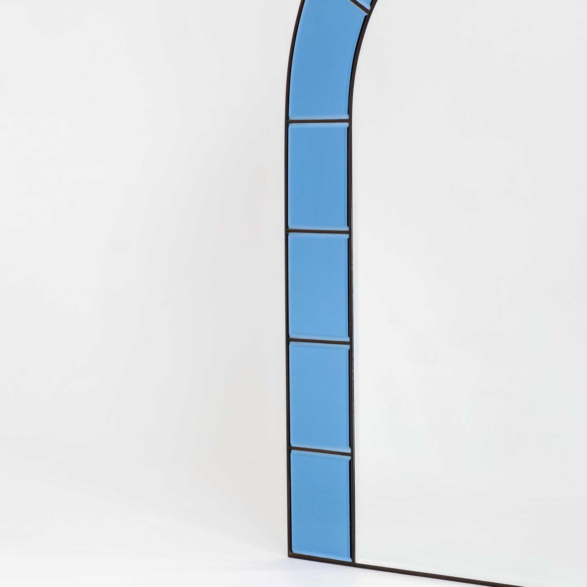 Großer bogenförmiger Wandspiegel mit schmalem Messingrahmen. Die Umrahmung besteht aus blauen Glasscheiben mit facettierten Kanten. Der Spiegel ist im Stil der italienischen Manufaktur Cristal Arte gestaltet.
