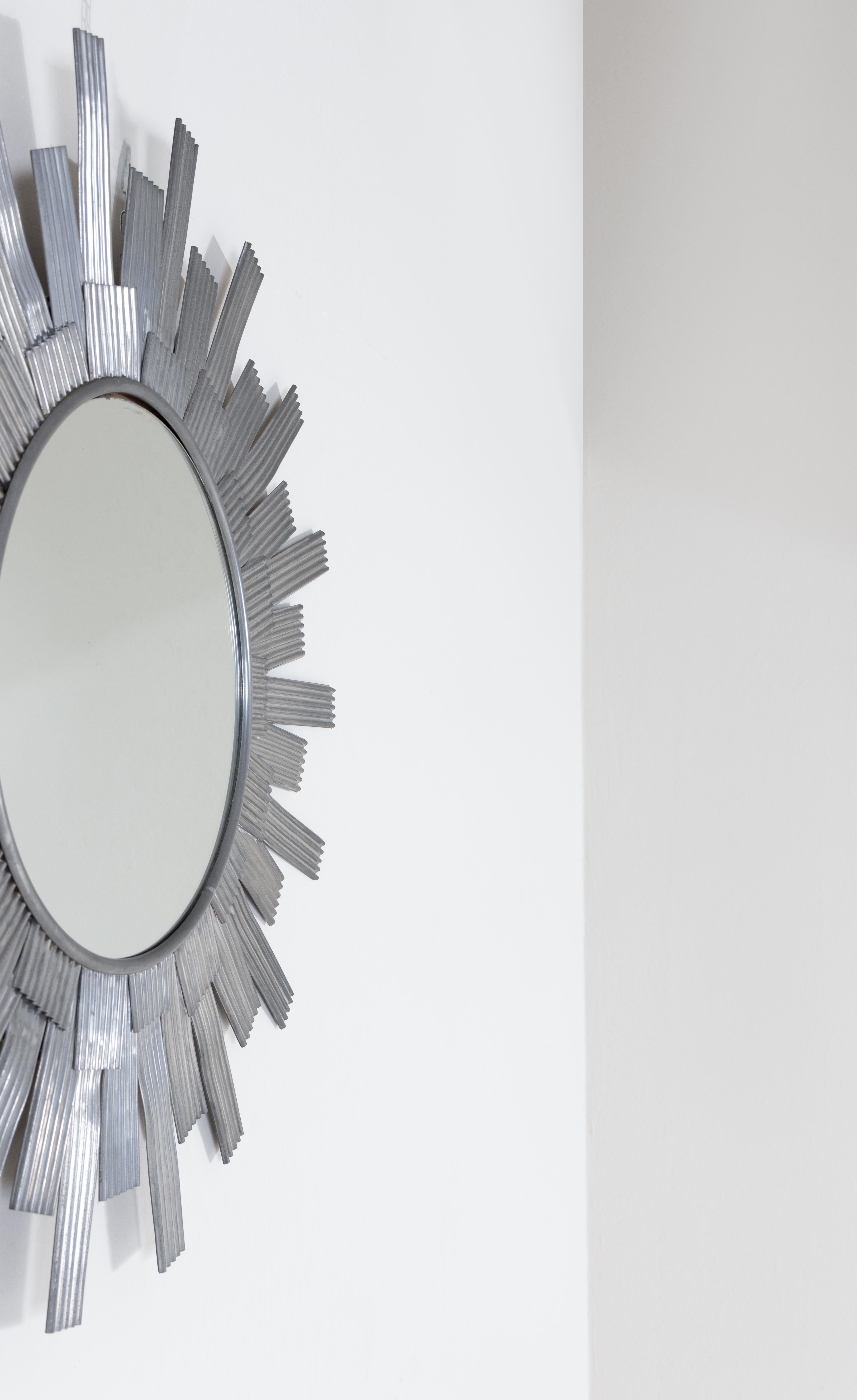 Miroir mural en tôle d'aluminium façonnée, produit par Bottega Gadda. Le travail du métal, typique de l'atelier milanais, met en évidence l'attention artisanale portée à la matière et la capacité à transformer un matériau industriel en élément
