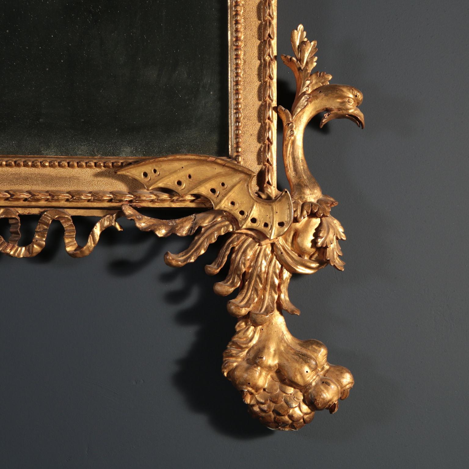 Gilded linden wall mirror richly and finely carved. The rectangular frame is carved and burin made with gold finishing; on the architectual fronton cymatium are leaning two chimeras with a classical taste carved flower vase in the middle; the vase