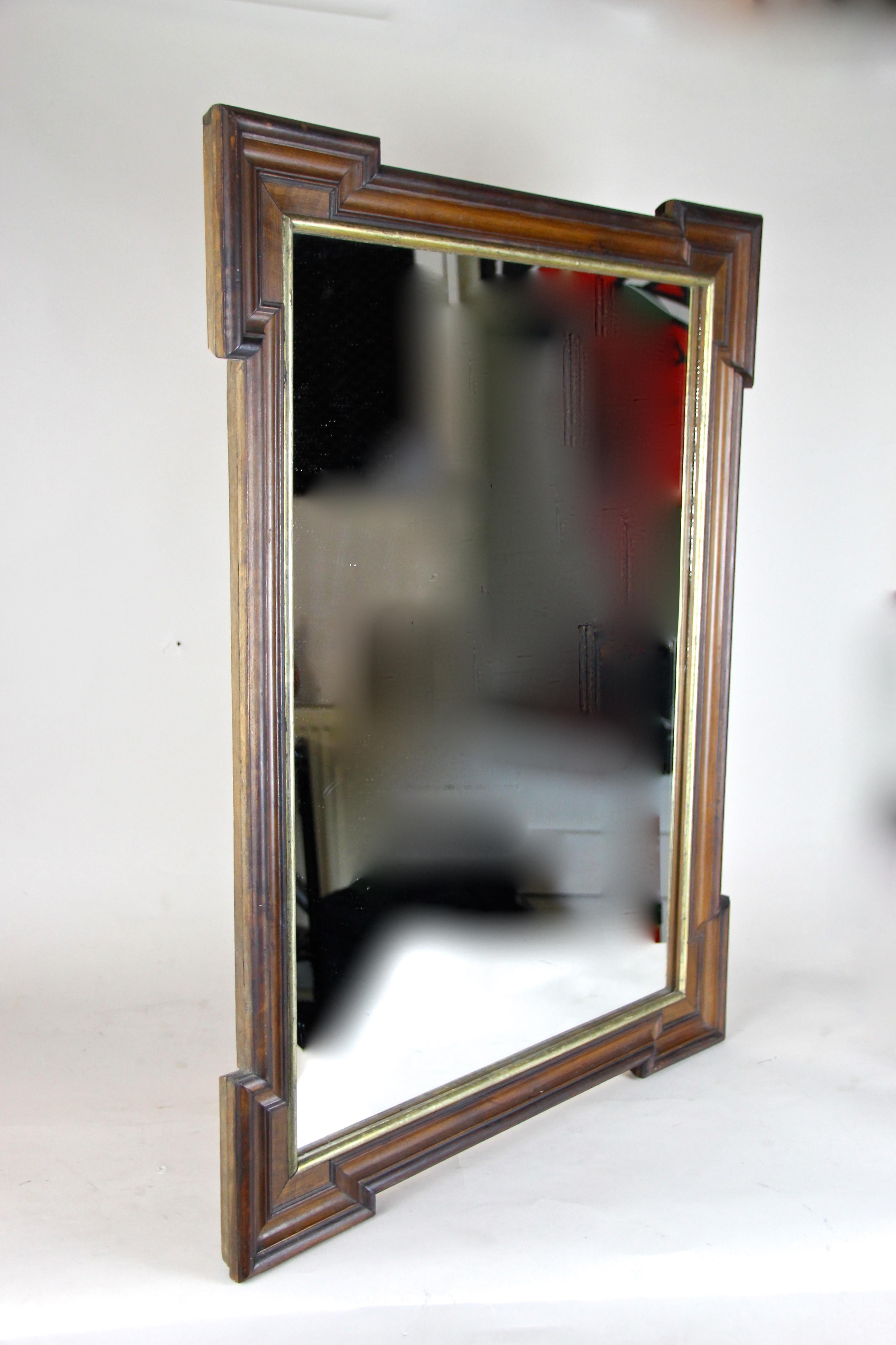 Made in beautiful Austria around 130 years ago, this large nut wood wall mirror shows an overlapping inserted substructure of spruce wood. The beautiful frame shows a unique design with different composed nut wood veneered bars. Elegant lines and