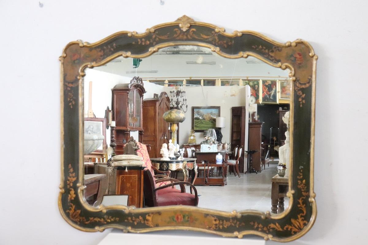 Ce beau miroir, qui attire l'attention, est doté d'un cadre en bois datant de la seconde moitié du XXe siècle. L'élégant cadre est décoré de laque dans de riches nuances de vert foncé, complétée par de charmantes décorations florales peintes. Ses