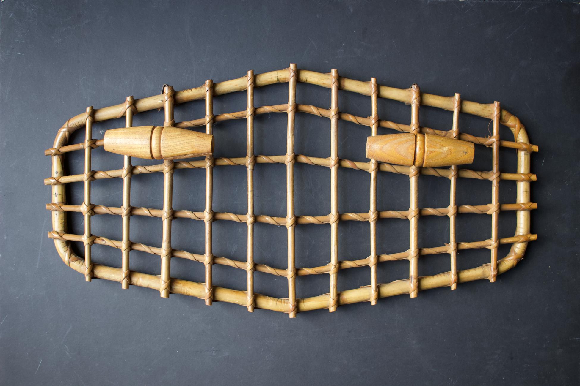 A simple wall-mounted coat rack with two wooden hanging points. Mid-20th century, Italy. 

Frame of bent bamboo in light to medium tones - best shown in the close-up images - overlaid with a grid of four cross bars and eleven uprights, bound with