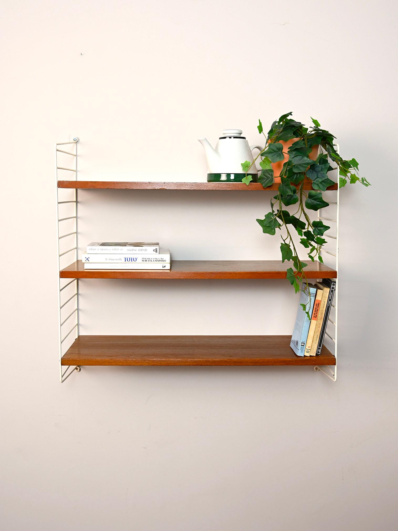 Original Swedish shelving system from the 1960s.

This simple shelving system consists of a coated metal side frame on which three wooden shelves fit.
Simple and functional it can be hung in different rooms of the house.

Good condition. It has been