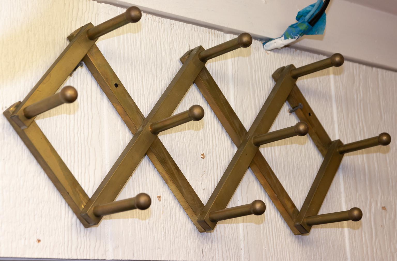 Circa 1960s Mid-Century Modern diamond shaped wall mounted brass coat rack with ten hooks. Due to its accordion construction the dimensions can be adjusted slightly. Please note of wear consistent with age. The brass shows slight signs of oxidation