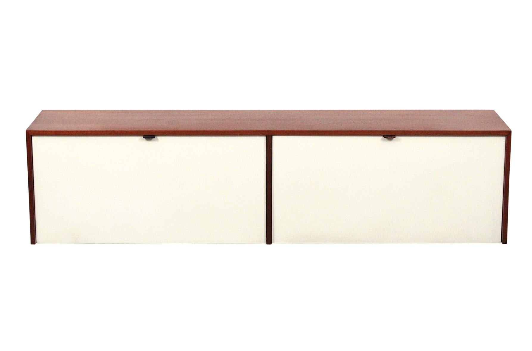 Wall-mounted cabinet by Florence Knoll for Knoll Associates. Walnut case with original white lacquered doors and interior. Interior has shelves of both oak and glass. This is cabinet model 