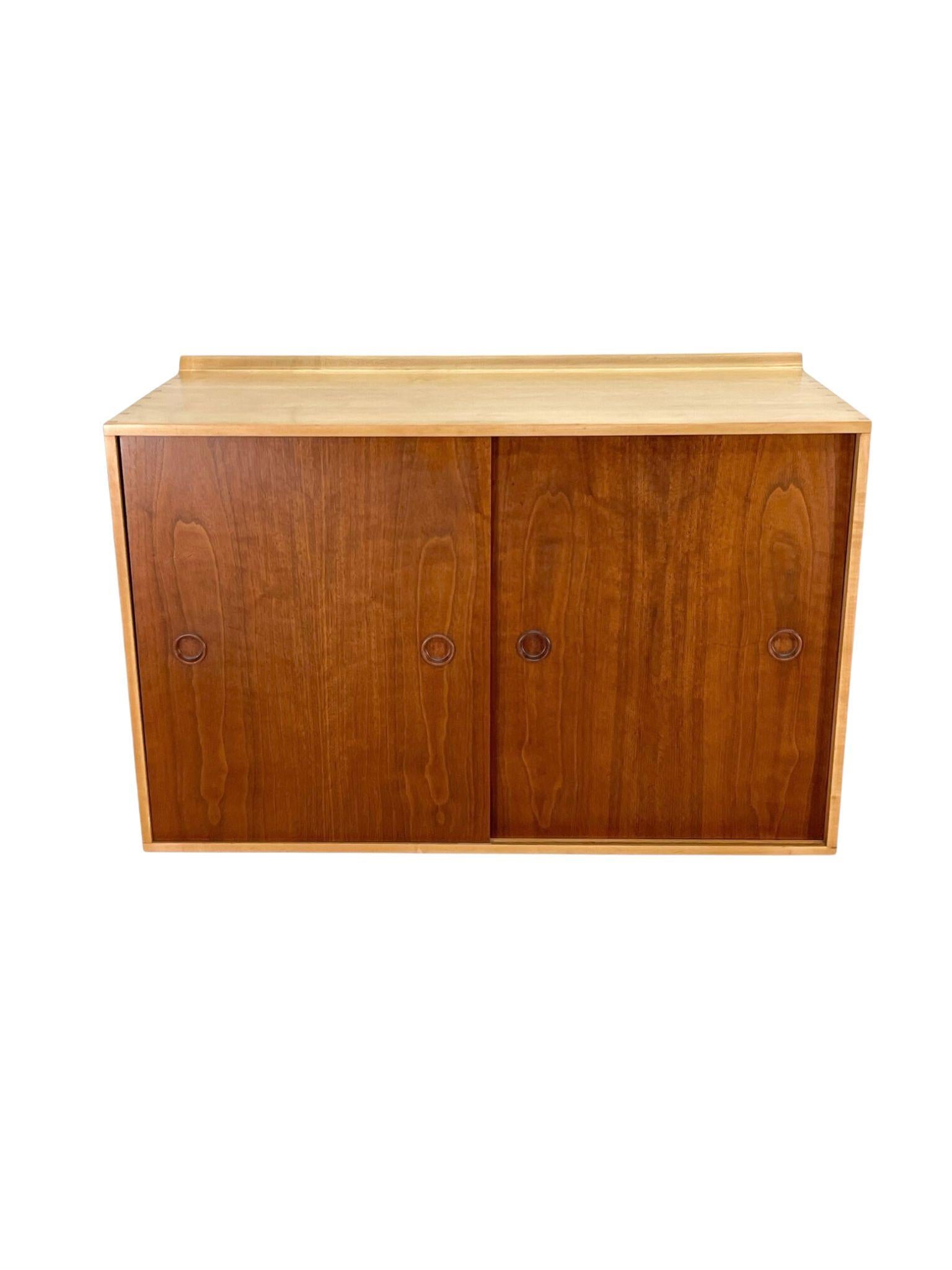 This is a wall mounted cabinet / console designed by Finn Juhl and manufactured by Baker, 1950s made from teak and maple. The beautiful grain pattern in the teak door fronts make for a striking contrast with the maple case.

Has interchangeable