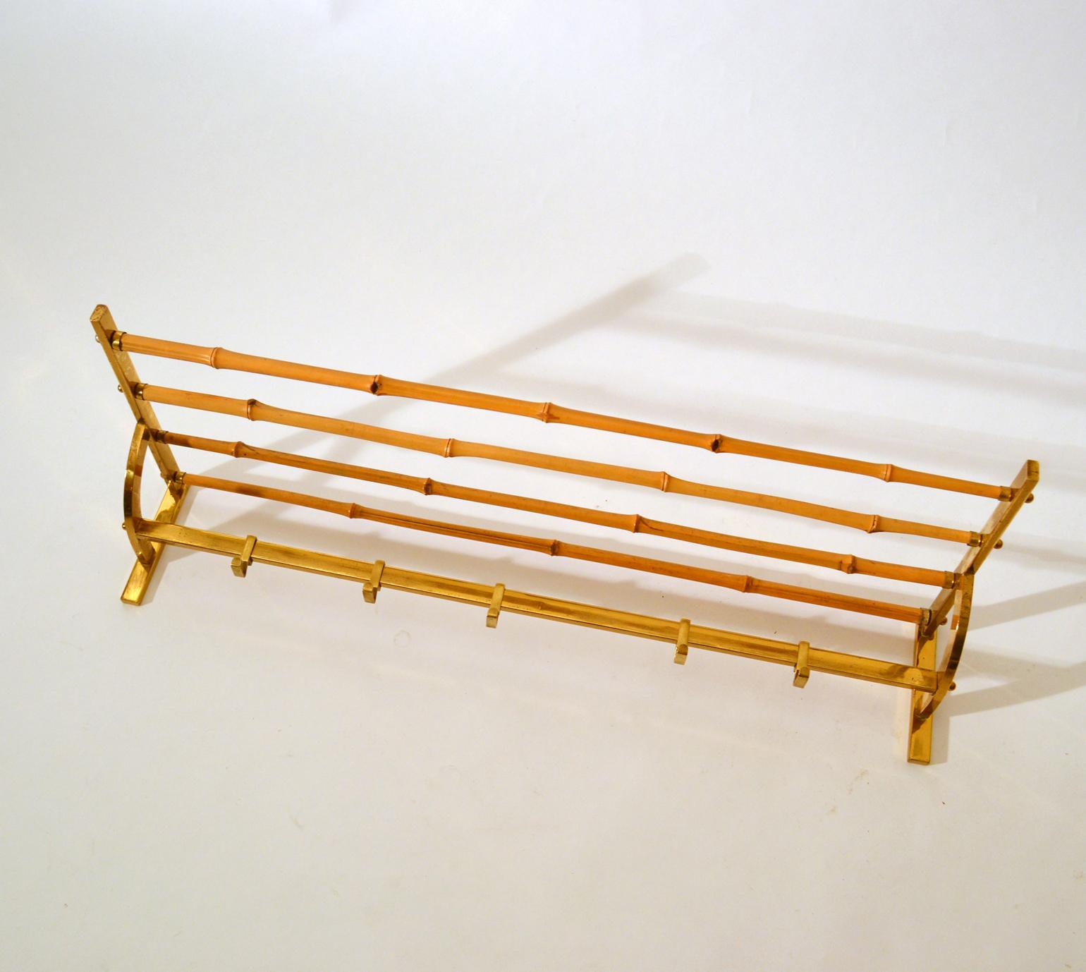 Wall mounted coat rack with five hooks in brass with bamboo hat rack attached.