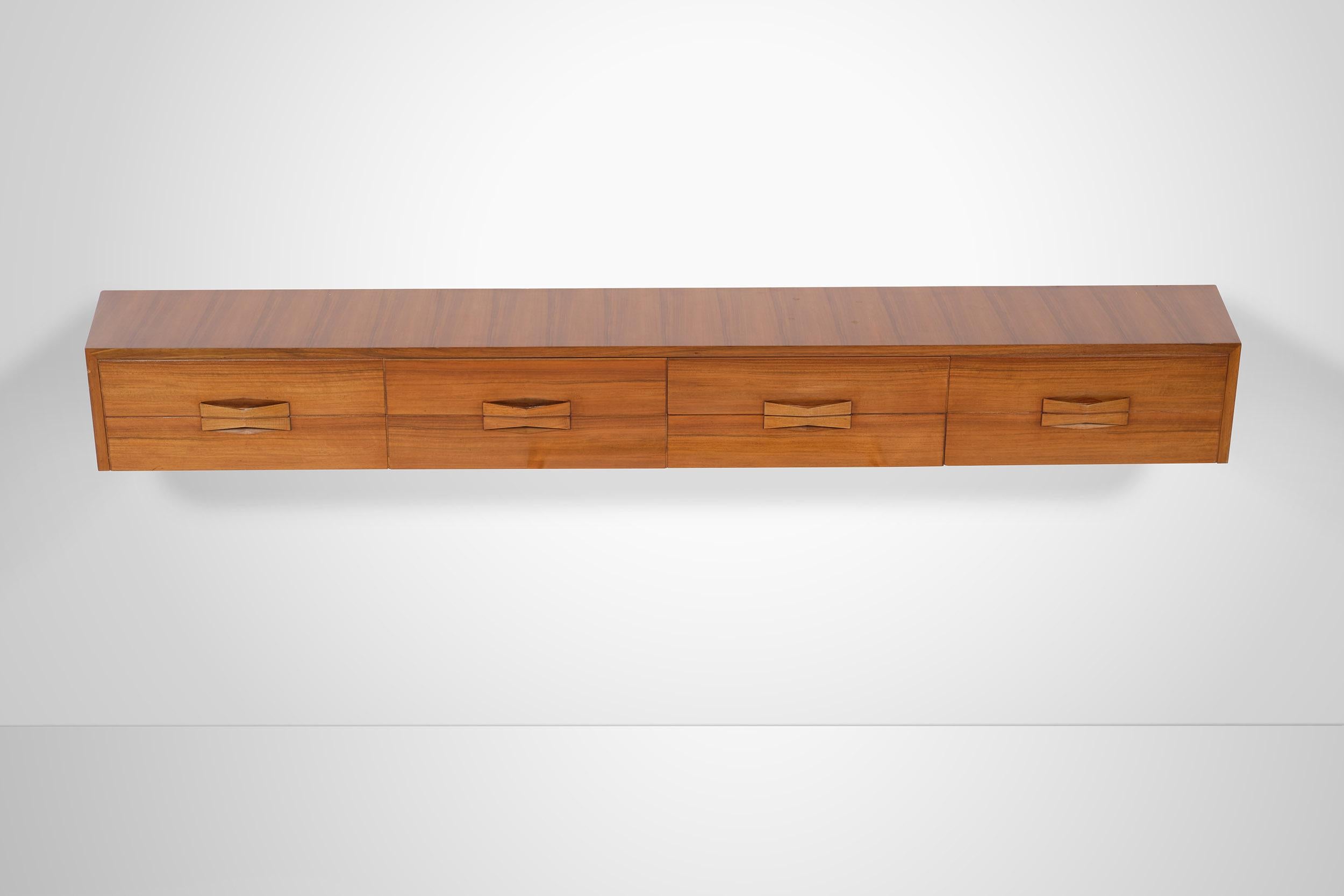 This wall mounted floating console in walnut was manufactured by Dassi in the '60s. Lightness and functionality find synthesis in this exceptional item featuring 4 spacious drawers embellished by elegant yet practical handles.
  