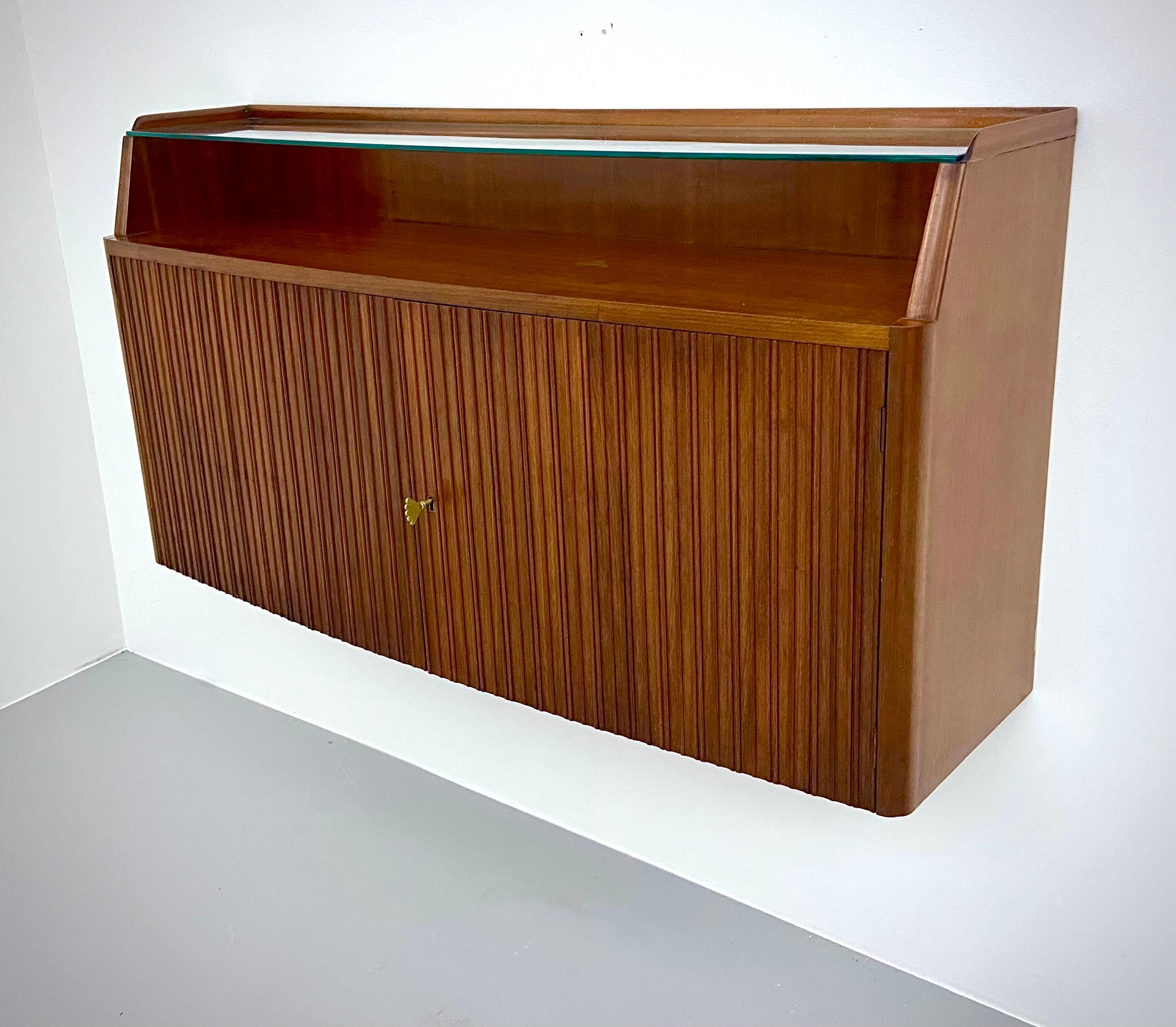Paolo Buffa wall-mounted ribbed credenza in patinated, brass and glass, by master woodmaker Serafino Arrighi, 1950's

What stands out in this small wall mounted credenza is the ribbed surface, the rounded forms and the not unimportant detail: the