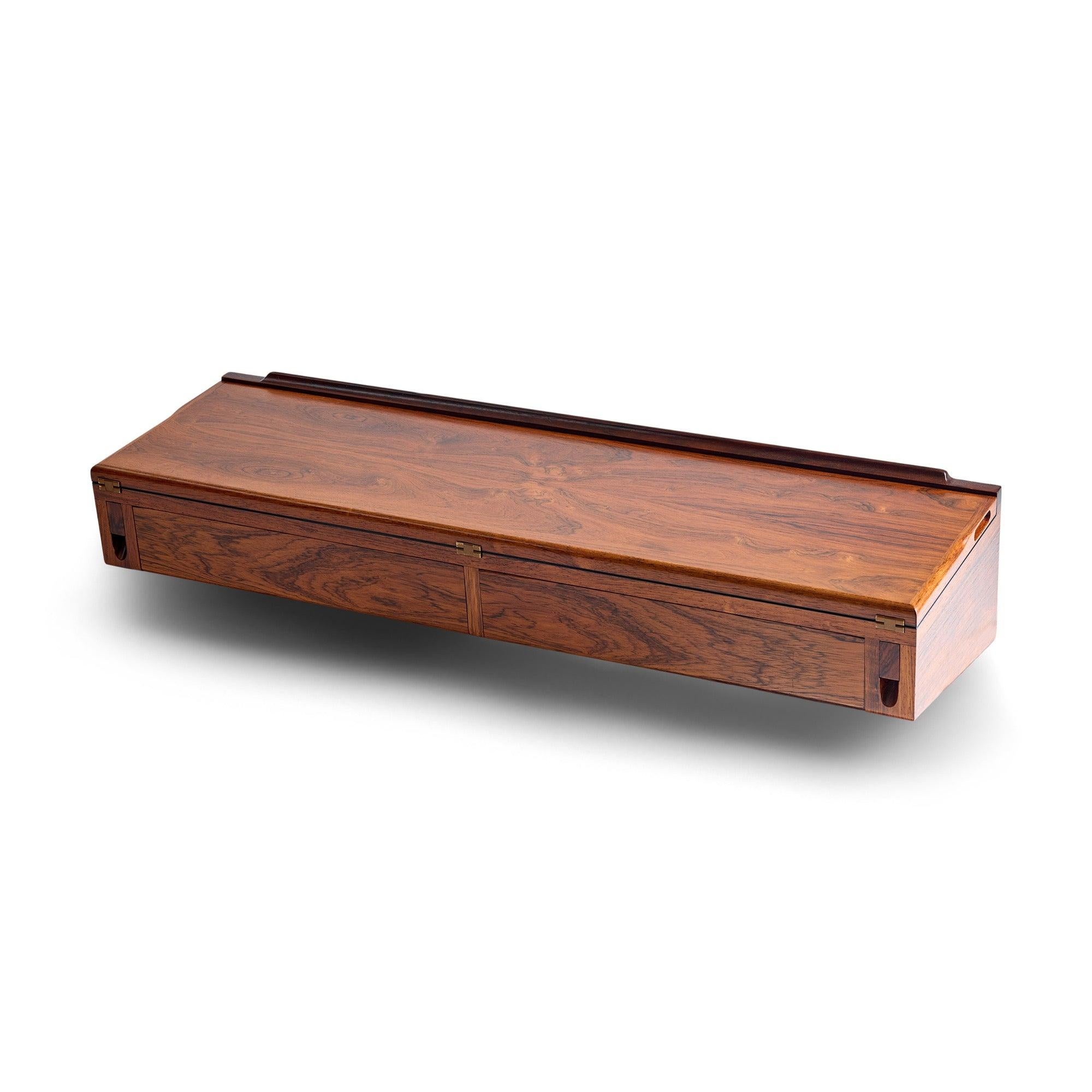 Una console da parete elegante e raffinata in ricco palissandro con due cassetti a filo e un piano incernierato (che rivela una superficie in laminato nero con deliziose cerniere in ottone a vista) che permette al pezzo di funzionare anche come