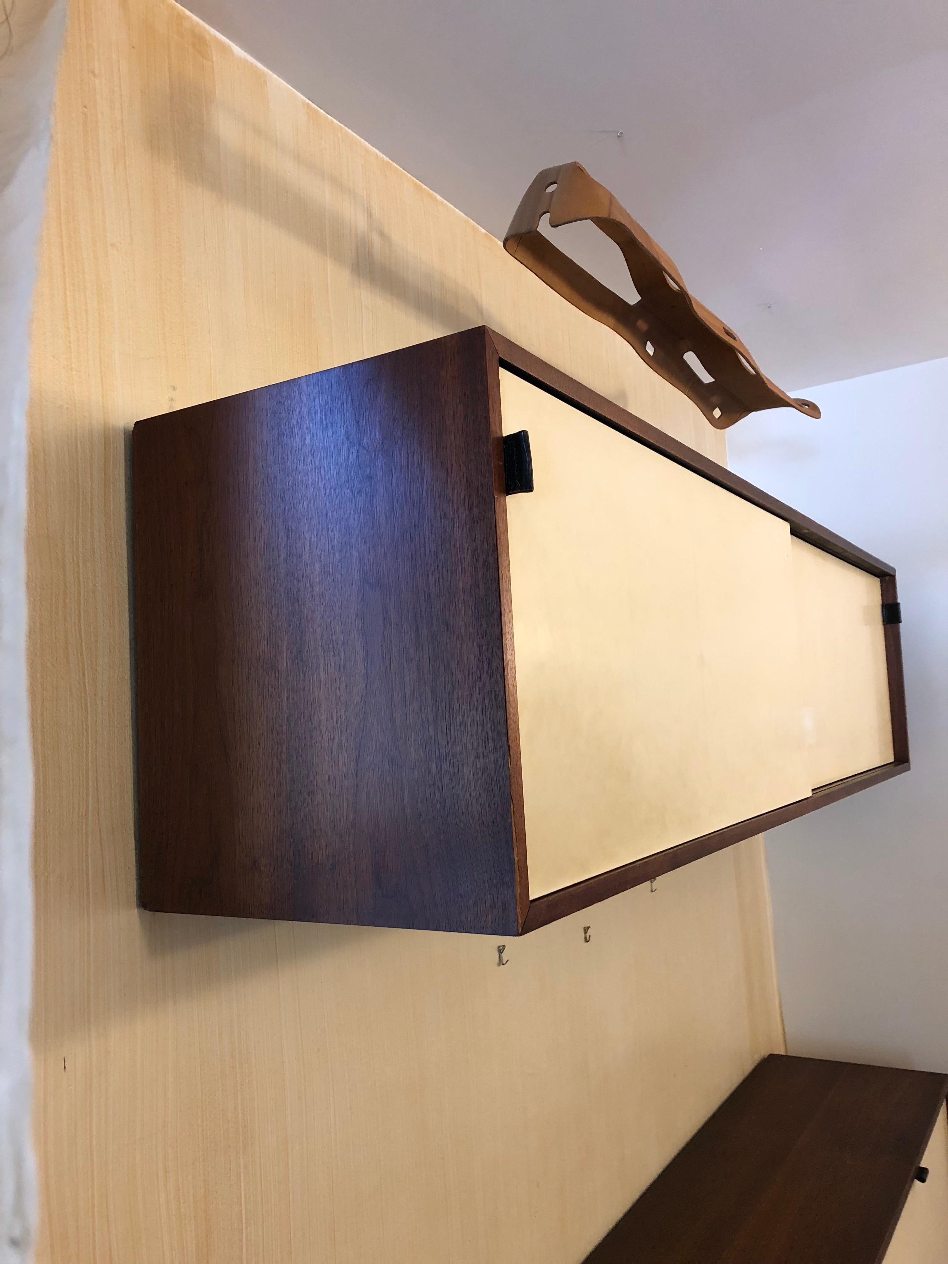 Classic walnut and lacquer sliding door credenza by Florence Knoll. Original leather pulls.