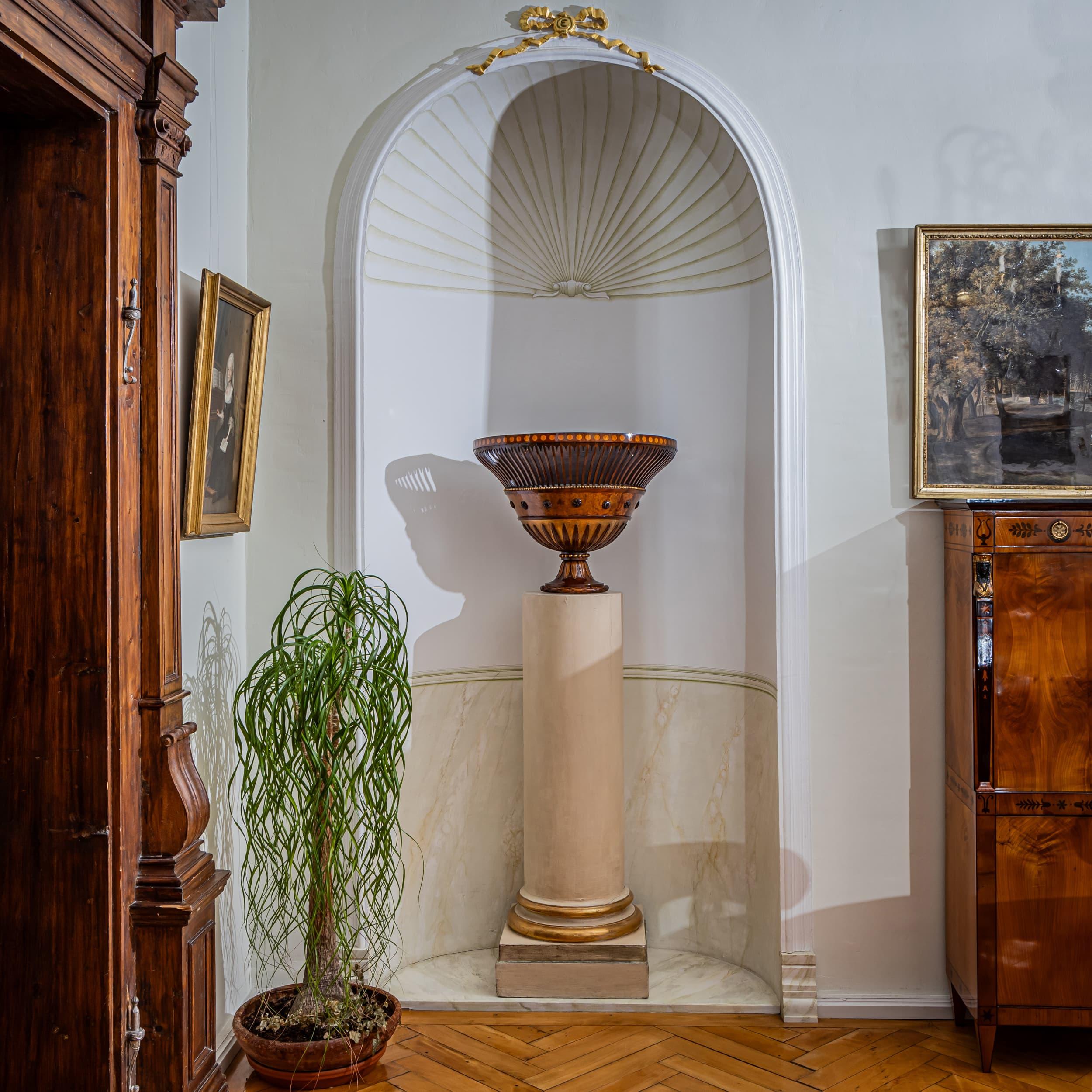 Panier à fleurs semi-circulaire en forme de vase, datant du 19e siècle. Le mur est orné de motifs de feuilles et de rosettes complexes, délimités par des montants verticaux. Une étroite bande de laiton perlée ajoute du détail, bien qu'il y ait
