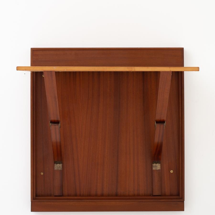 Wall mounted folding desk in mahogany and natural leather with brass handle. Maker Rud. Rasmussen.