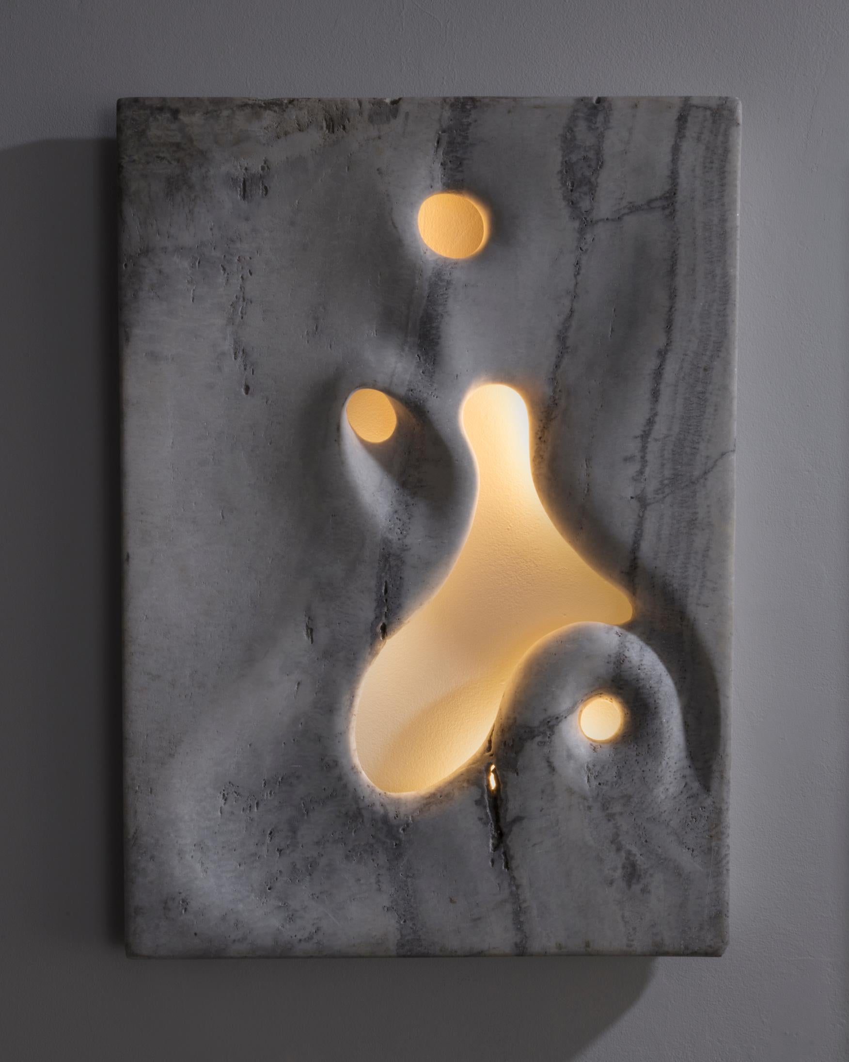 Unique wall-mounted illuminated sculpture in hand carved white travertine. Designed and made by Rogan Gregory, USA, 2016.
 