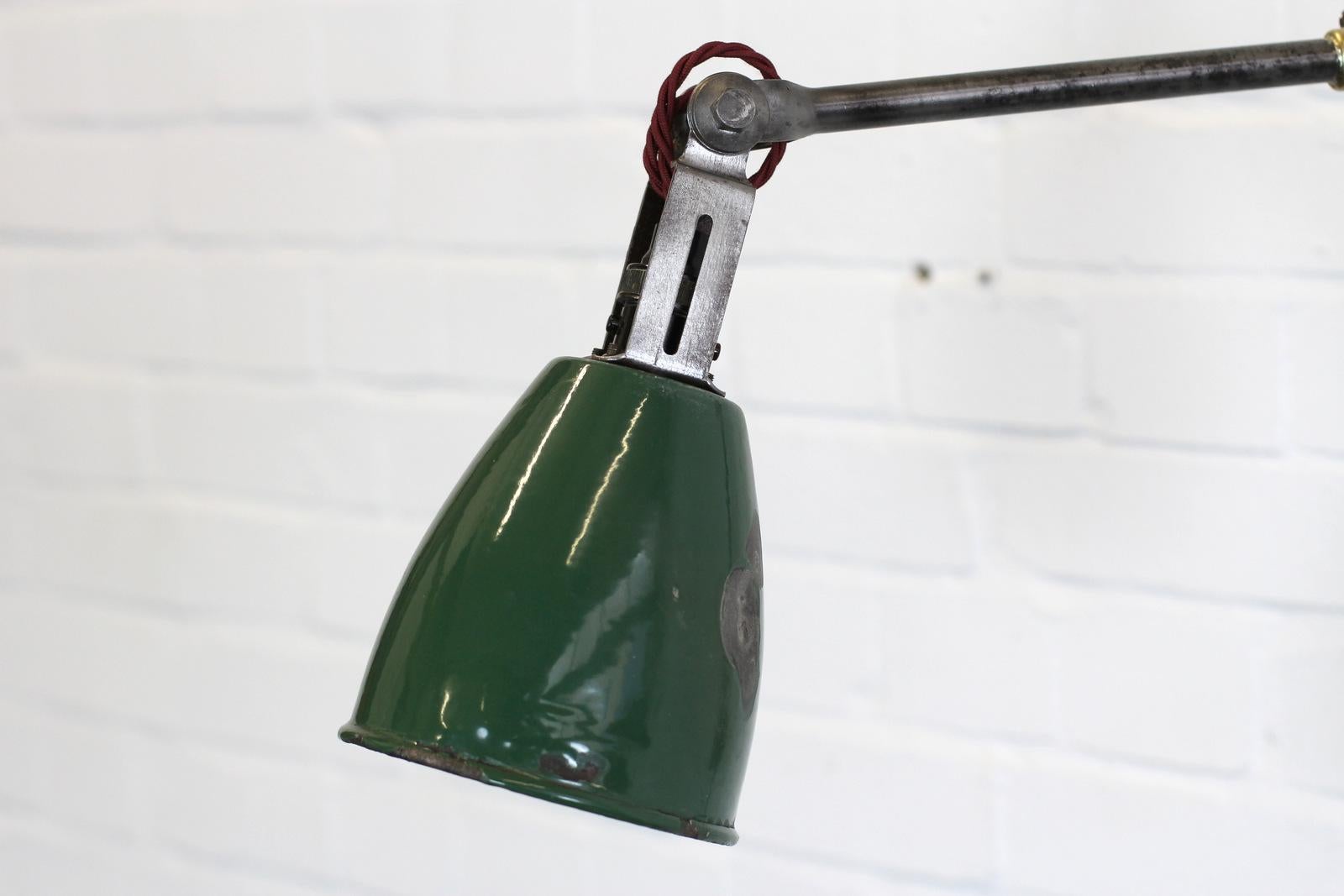 Wall mounted Industrial task lamp by Dugdills, circa 1940s.

- Articulated steel arms
- Vitreous green enamel shade
- Relief makers mark on the base
- Takes B22 fitting bulbs
- Original bakelite switch
- English, 1940s.
- Extends up to 80cm