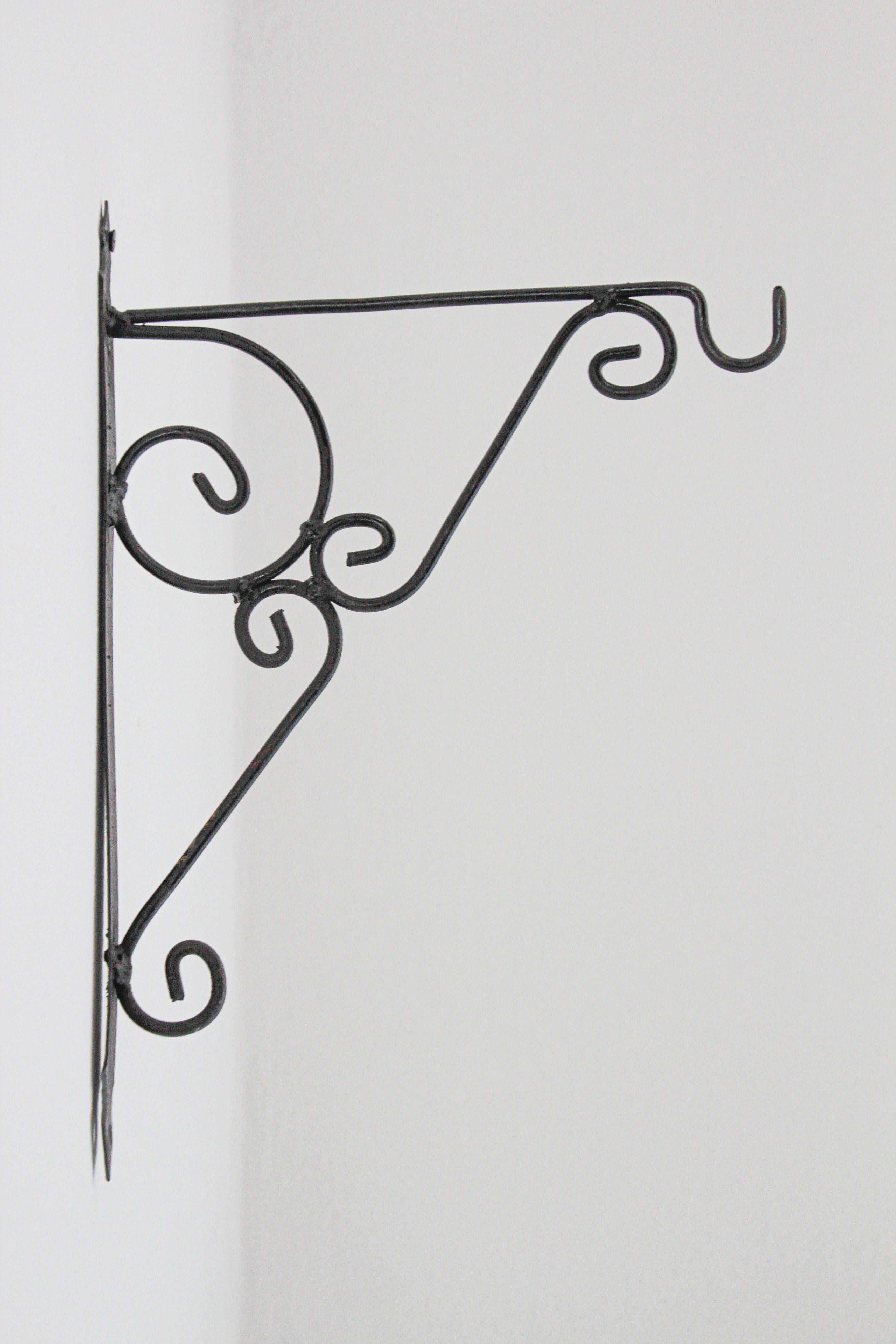 Hand crafted iron scroll design wall bracket. 
Vintage wrought iron handcrafted wall-bracket for lanterns or signs.
Perfect for hanging lights or plants outdoors.
Scrolling wall-mounted iron brackets.
Multiple available.
Dimensions: Projection: