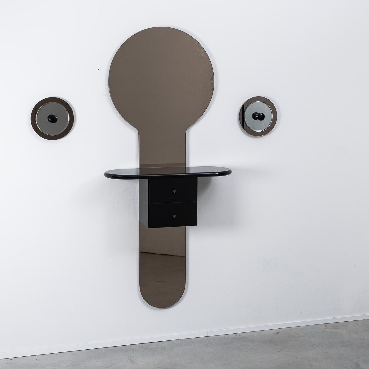 This playful wall-mounted mirror console caught our eye in Italy. The striking shape is created from a central piece of tinted mirror, intersected by a drawer unit seen to levitate in the middle. It also comes with two hooks, hanging mirrored disks,