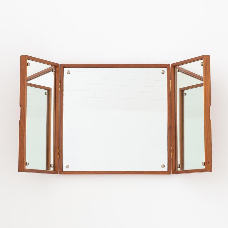 Wall-mounted, three-winged mirror in teak with brass brackets. Maker Ludvig Pontoppidan.