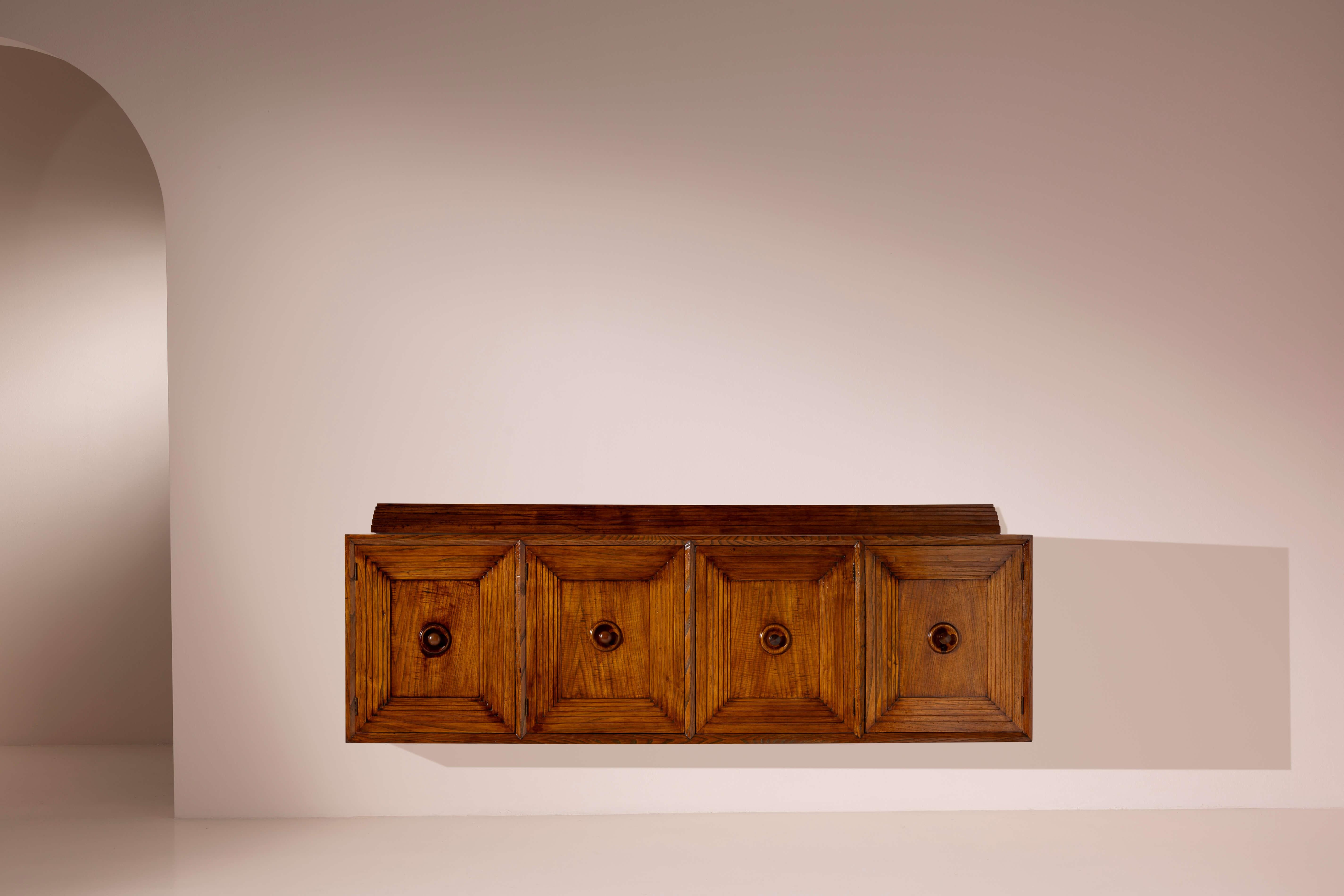 A large wall-mounted sideboard with four paneled doors, oak wood, Italian manufacture, 1950s

Designing a wall-mounted cabinet presents a unique challenge for both renowned designers and skilled cabinetmakers. Creating a piece that, without the